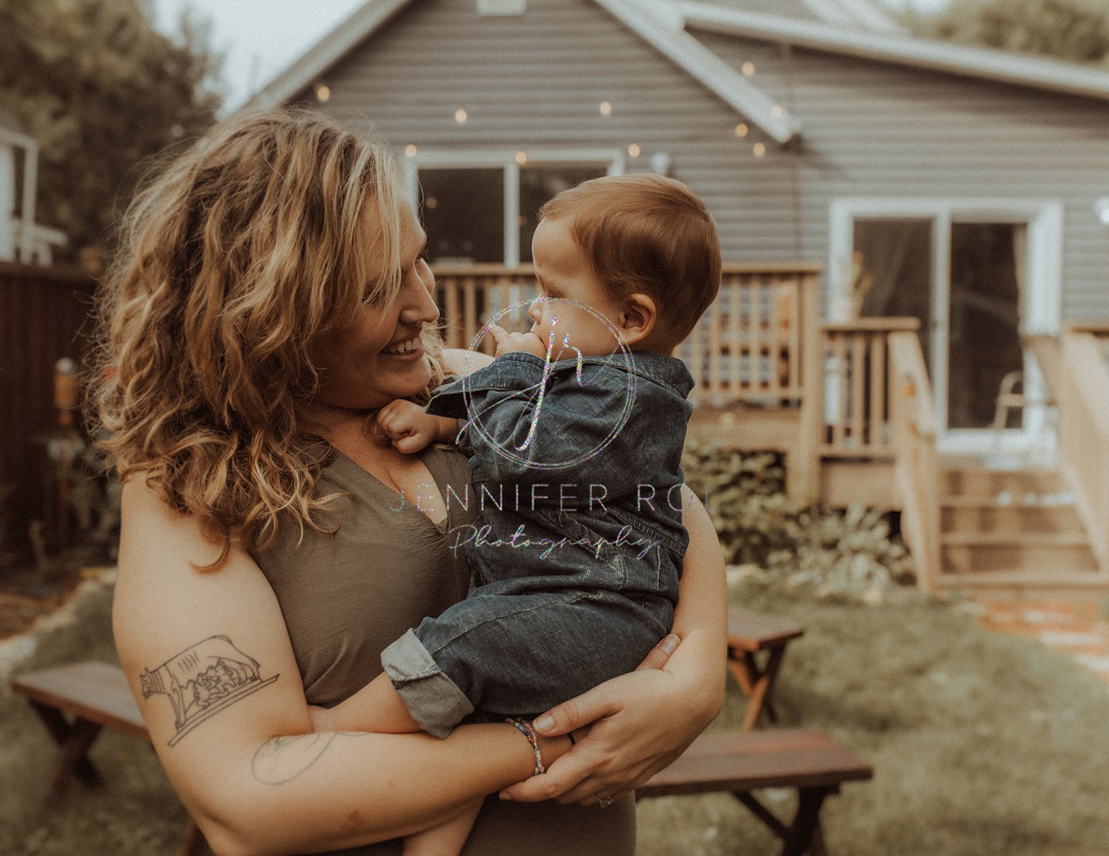 A happy mom plays with her toddler in her arms in her backyard