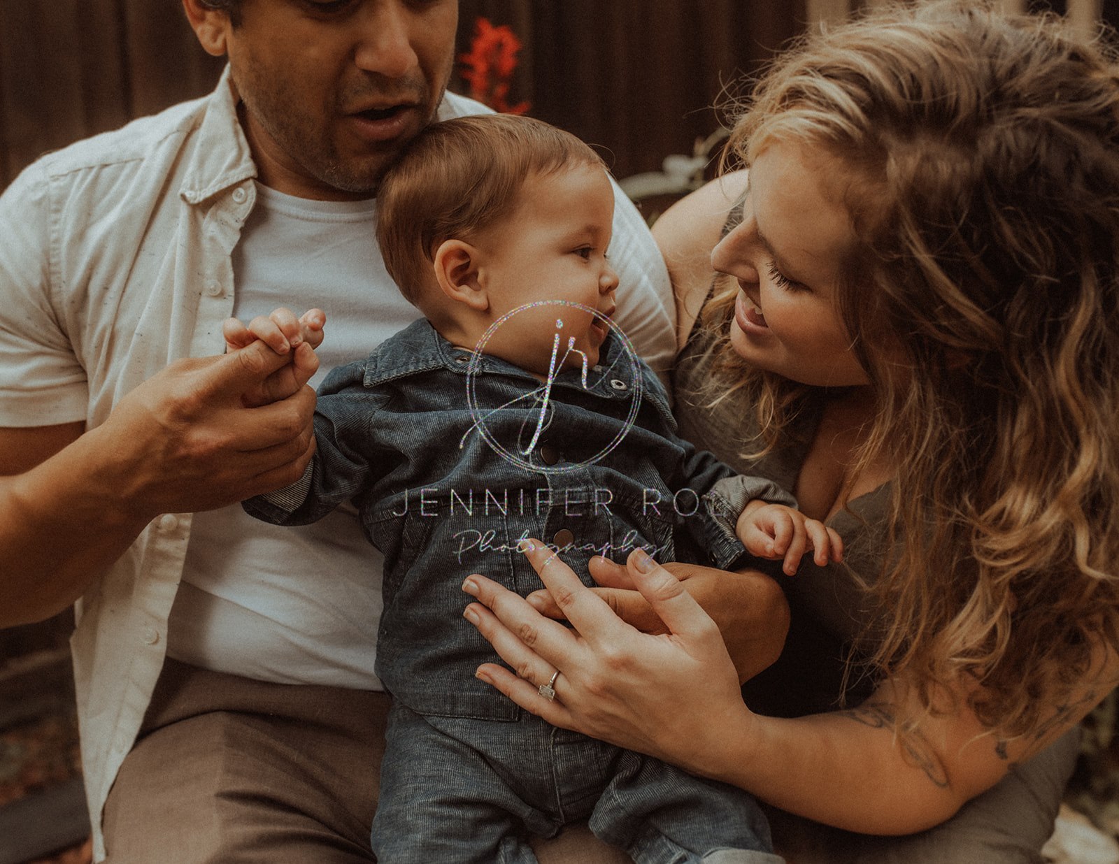 Happy parents play with their infant son in denim onesie before visiting baby stores in Missoula