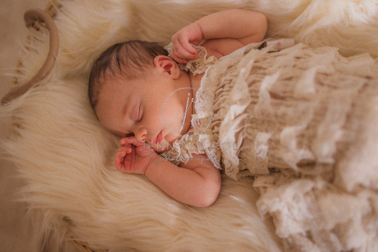 A newborn baby girl in a white ruffle dress sleeps in a basket on a fur blanket after meeting Big Sky Nanny