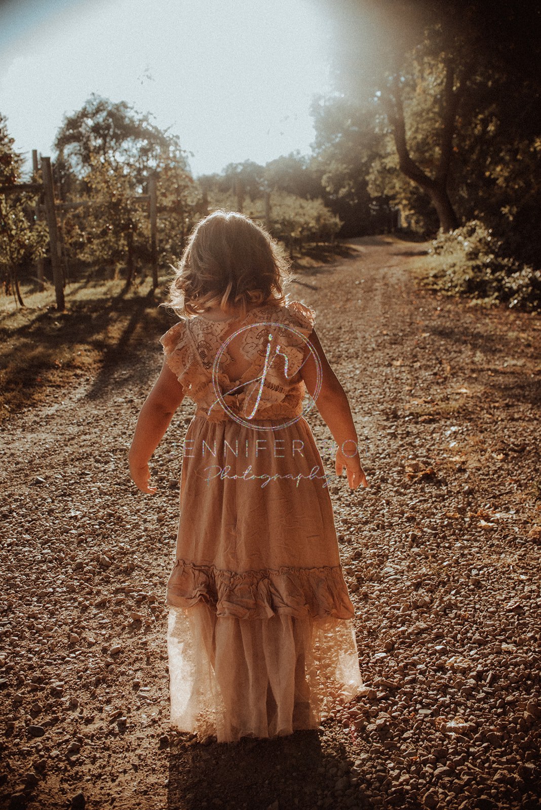 A toddler girl in a pink dress explores a park path at sunset before visiting Daycares in Missoula