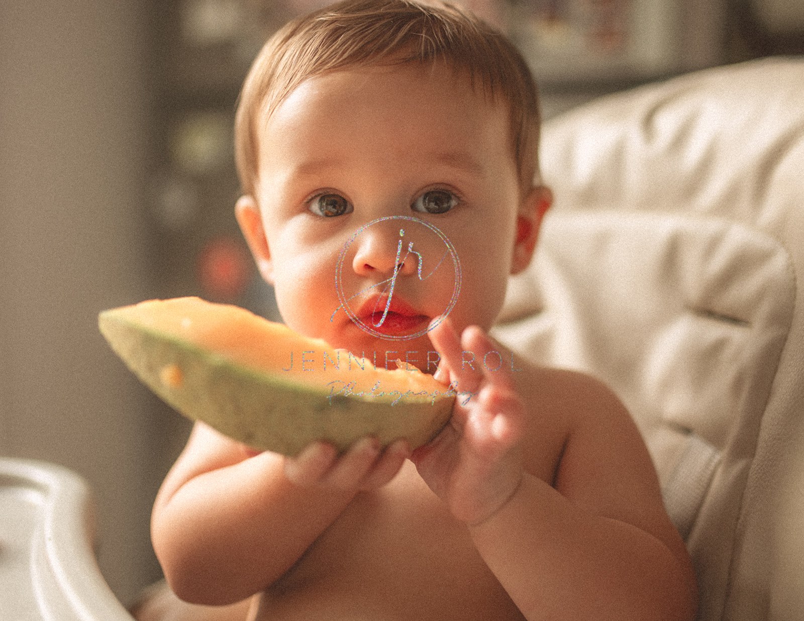 A toddler boy eats a cantaloupe slice while sitting in a high chair after visiting pediatric dentists in Missoula