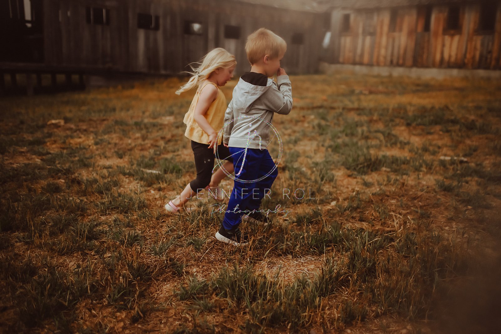 Toddler siblings play and run in a field together after visiting pediatricians in Missoula