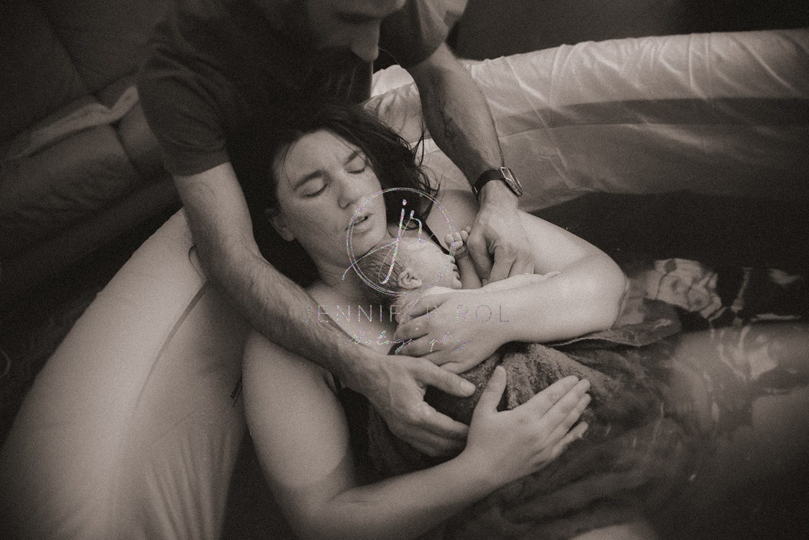 a relieved new mother cradles her newborn while still in the birth tub after a prenatal massage in Missoula