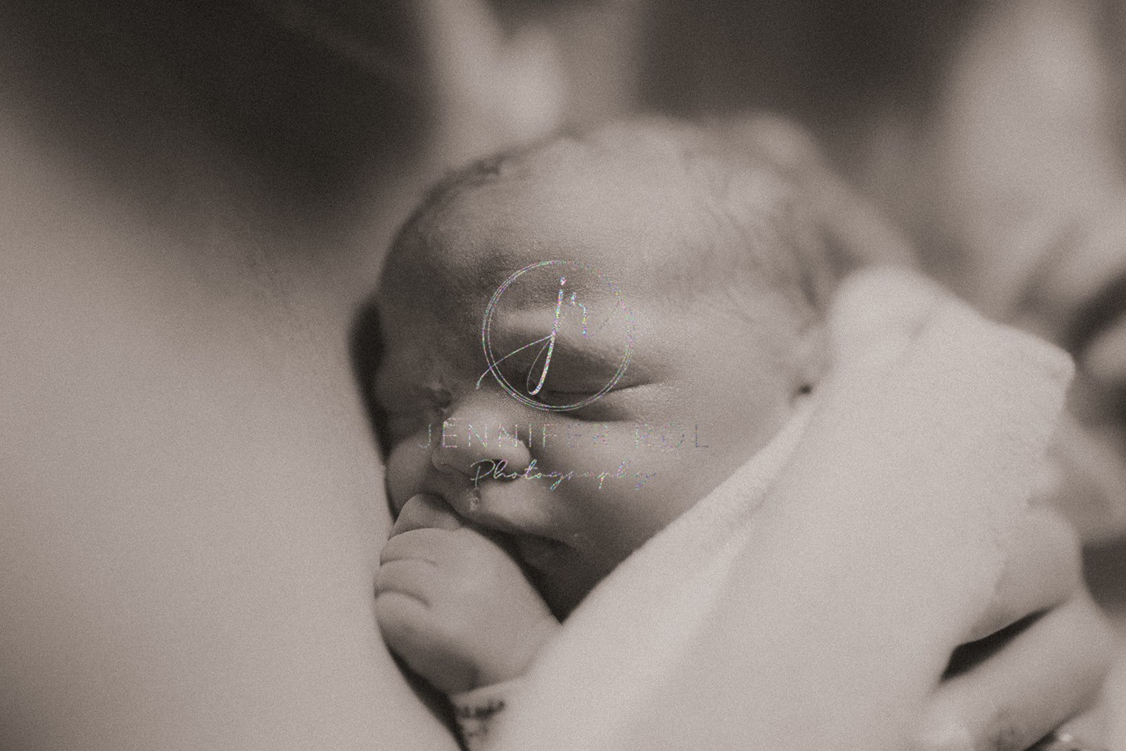 Details of a sleeping newborn baby under a blanket on mom's bare chest