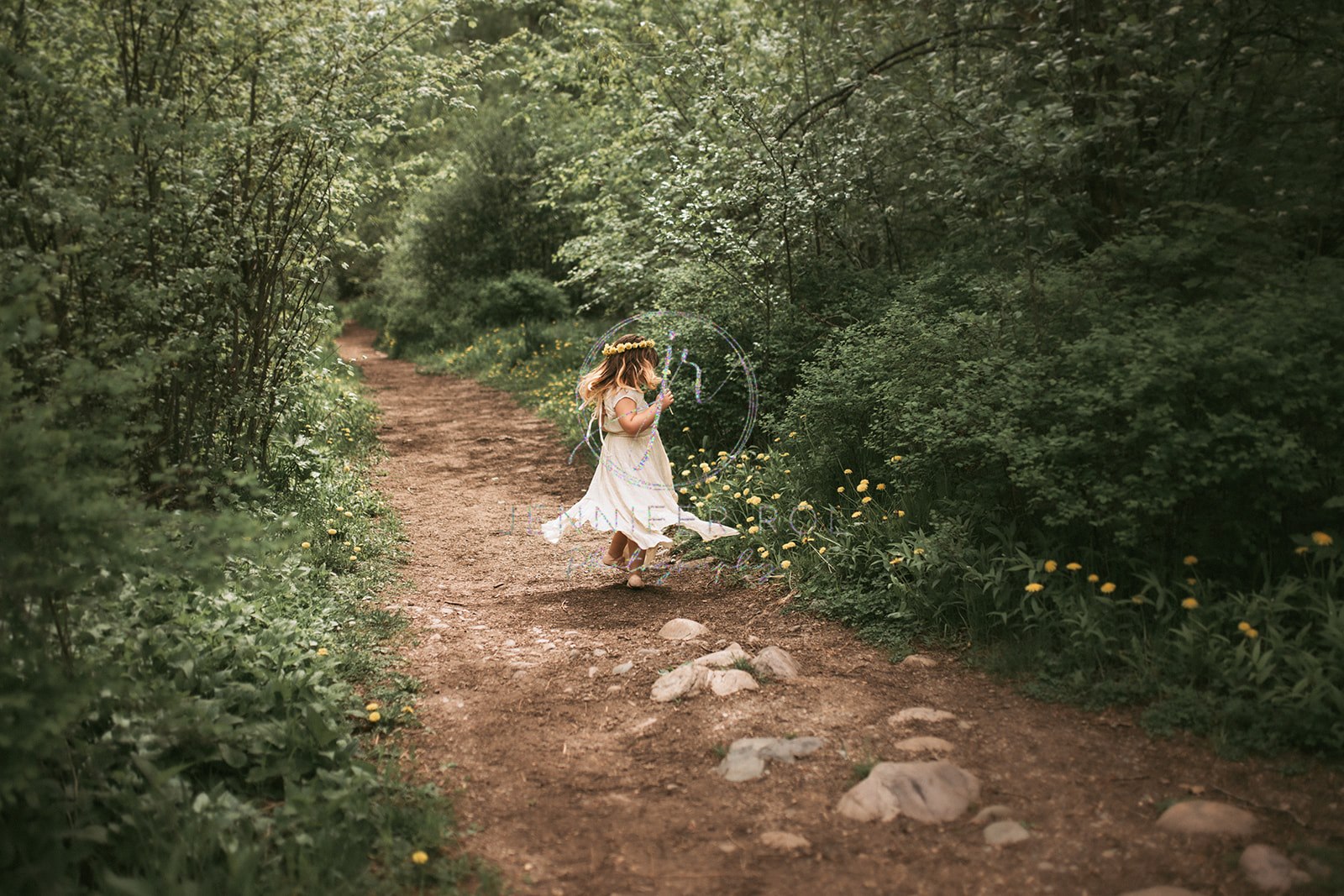 A toddler girl twirls and dances in a trail in a white dress after visiting Missoula birthday party places