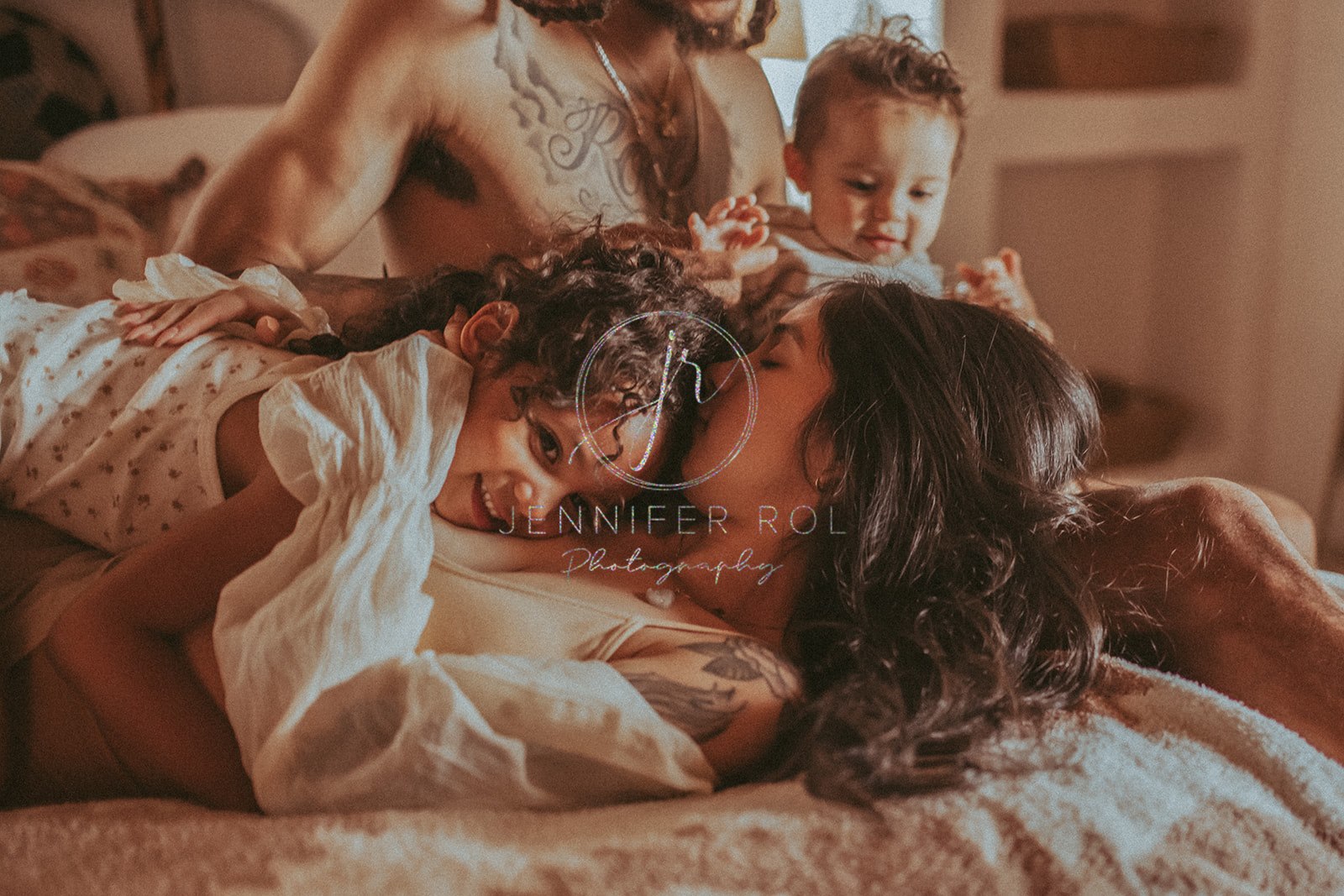 A happy family of four plays on a bed together after some Missoula toddler activities