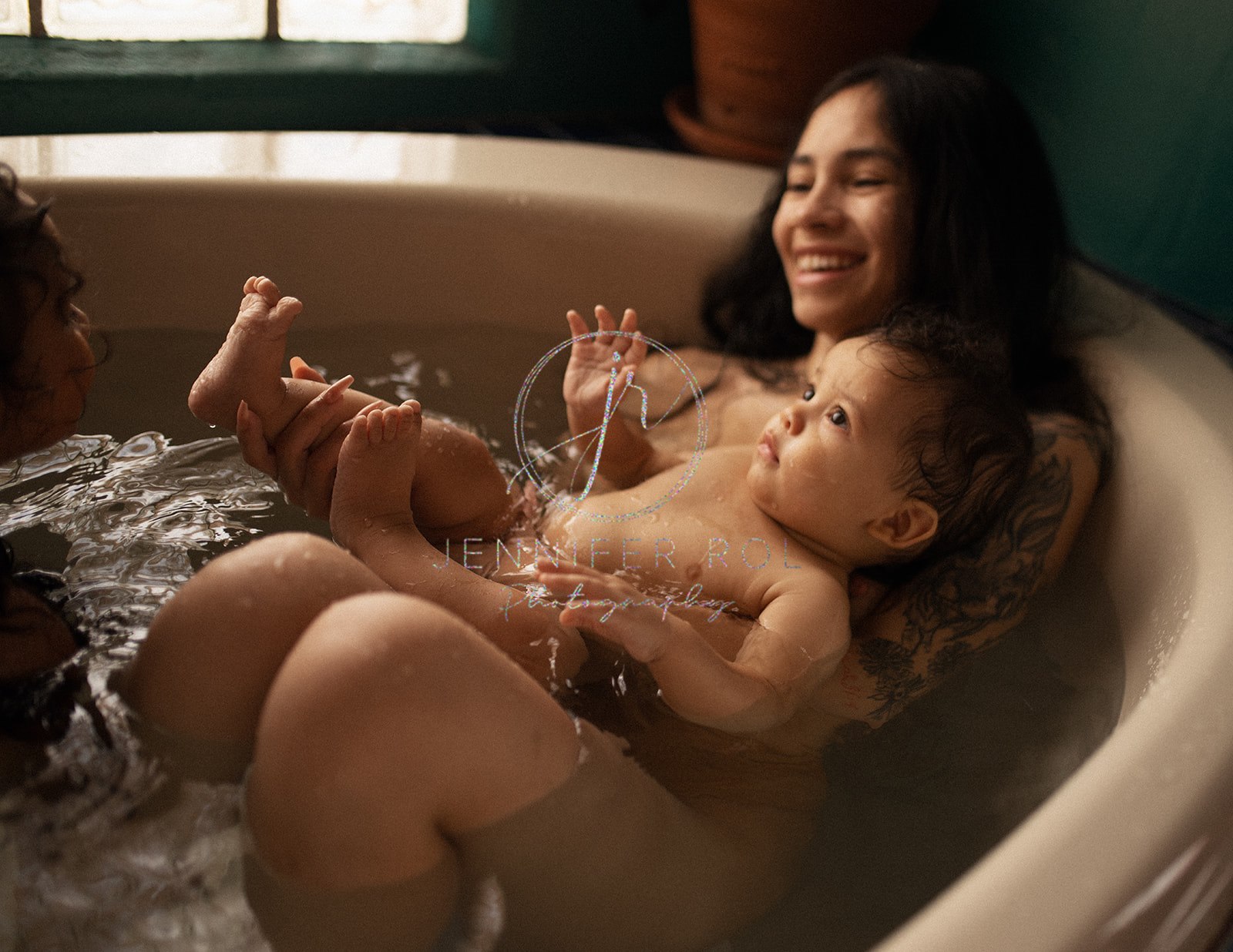 A happy mom plays in the tub with her infant son under a window after some parenting classes in Missoula