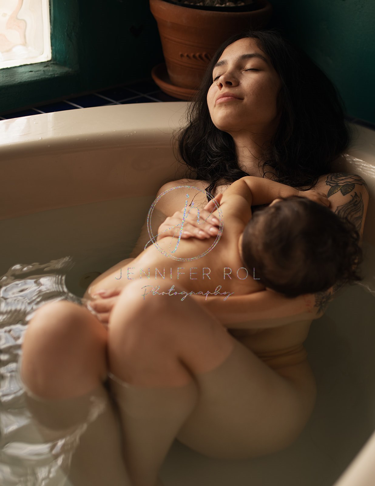 A happy mom sits in a bathtub breastfeeding her infant after some parenting classes in Missoula