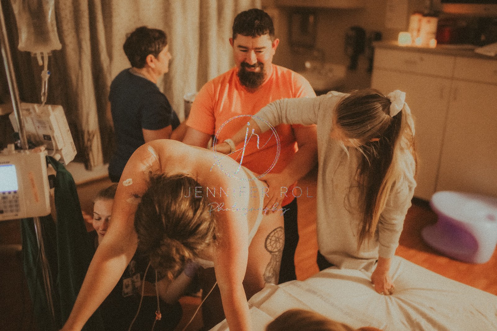 A mom to be leans on the hospital bed with her husband holding behind her as she deals with contractions after some prenatal yoga in Missoula