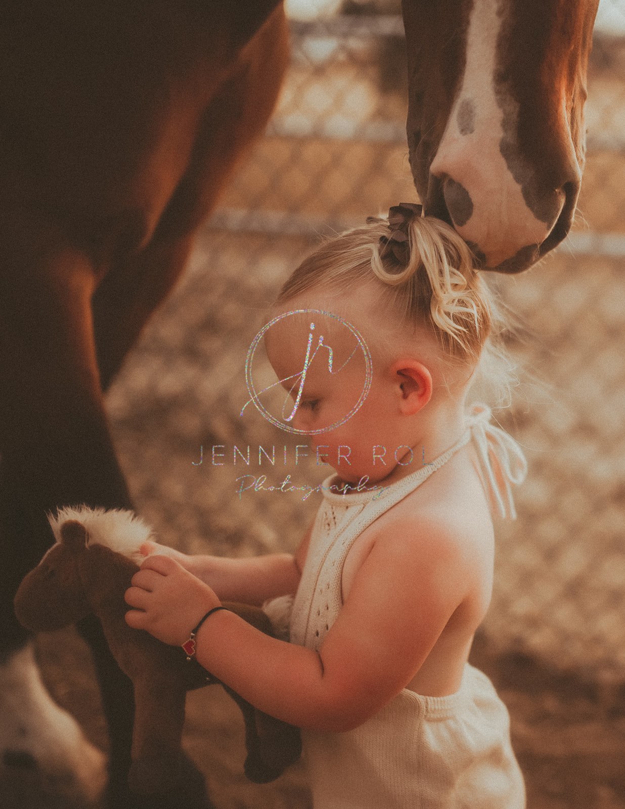 A toddler girl plays with a stuffed horse as a real one sniffs her hair after visiting Preschools in Missoula