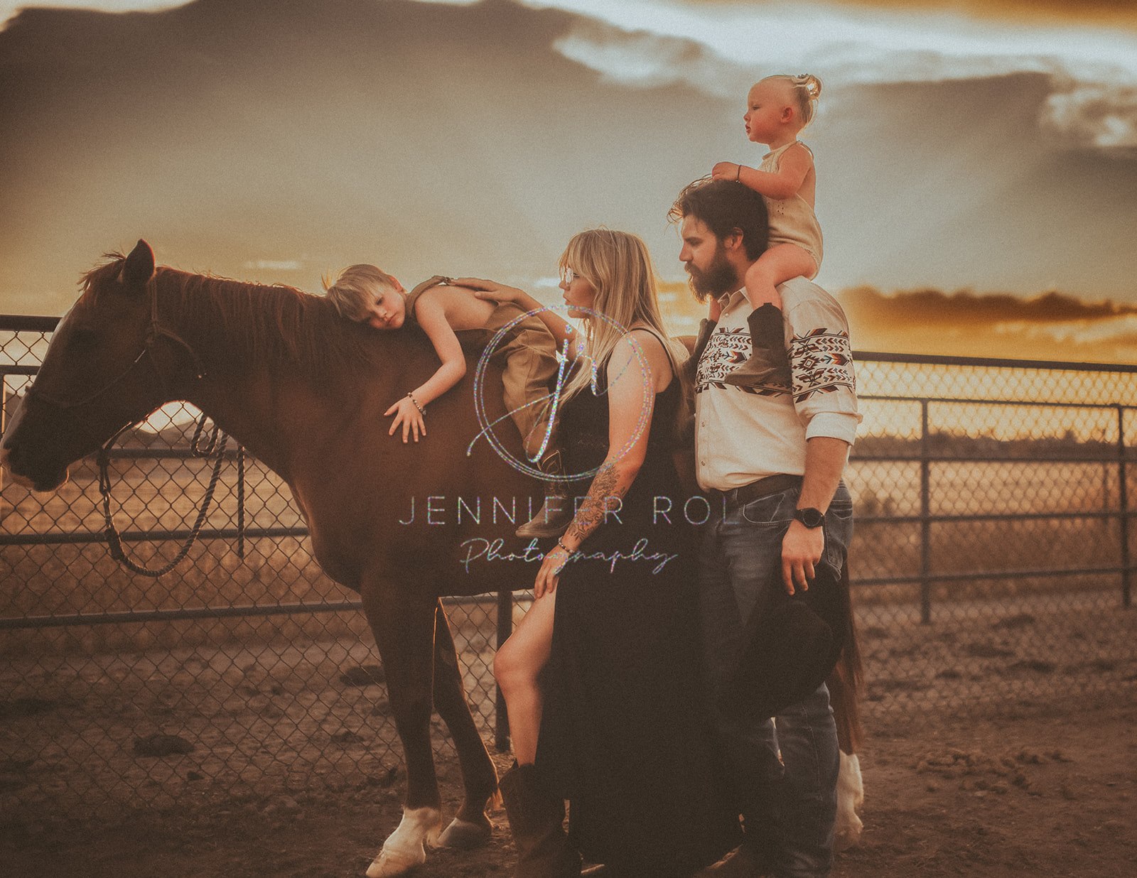 a toddler in overalls lays on top of a horse with mom and dad standing with him with baby sister on dad's shoulders after visiting Preschools in Missoula