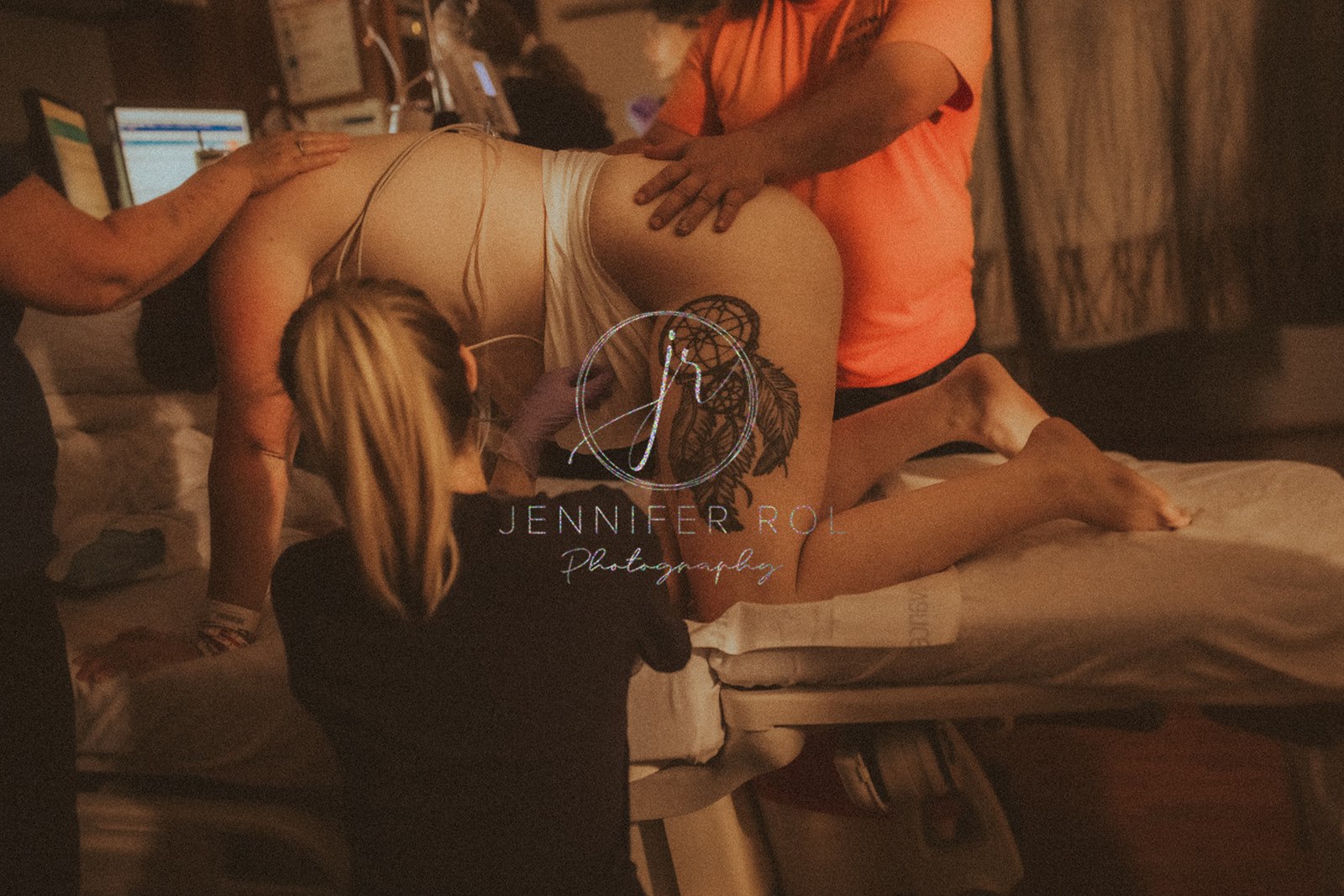 A mom to be in labor kneels on a hospital bed while dad helps hold her with a midwife checking after visiting Alpine Physical Therapy