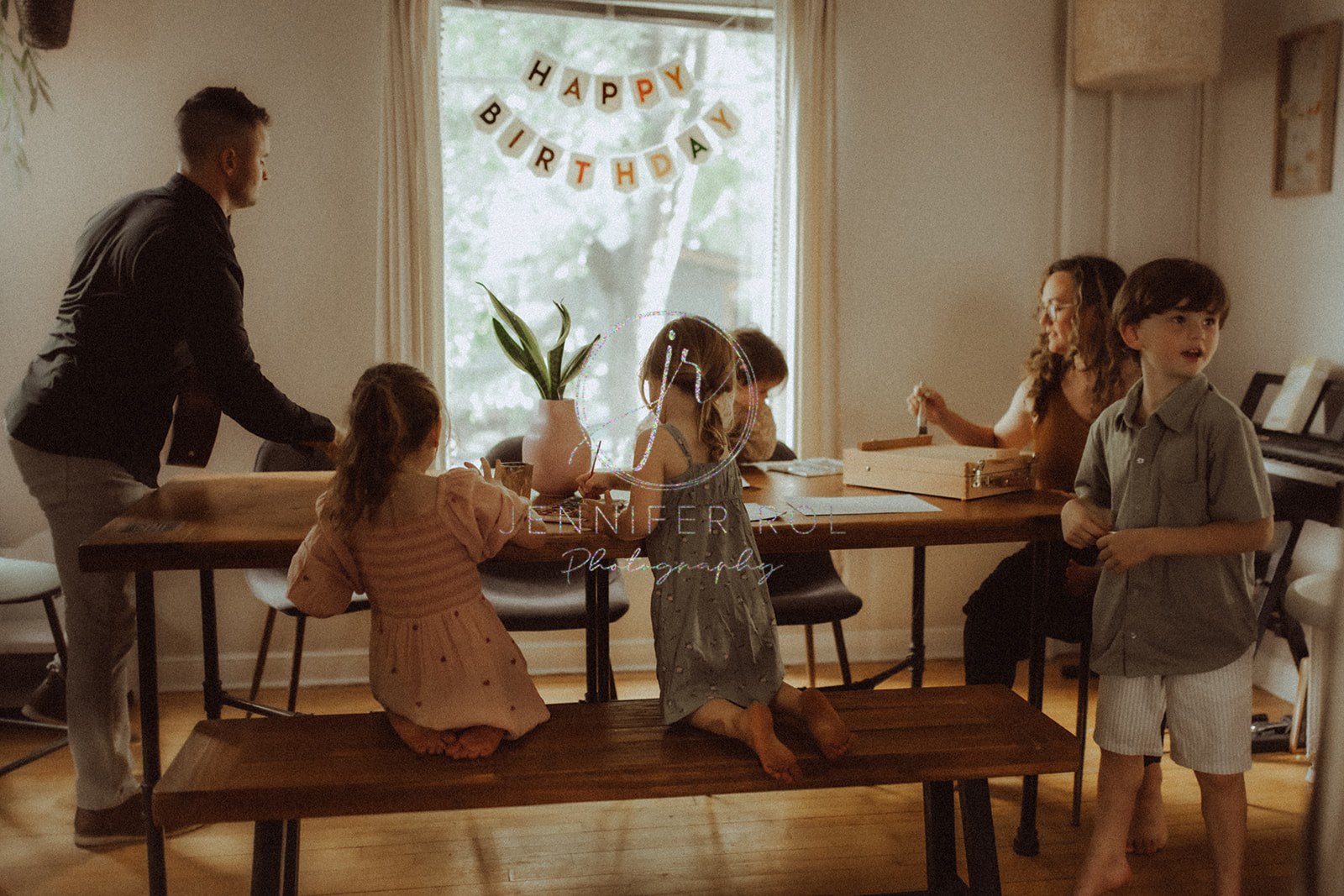 A happy family of 7 play and color at a long wooden dinner table in their house