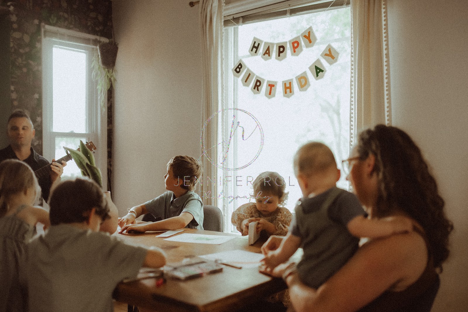 A happy family sits around the table coloring and painting and playing guitar before visiting family restaurants in Missoula, MT