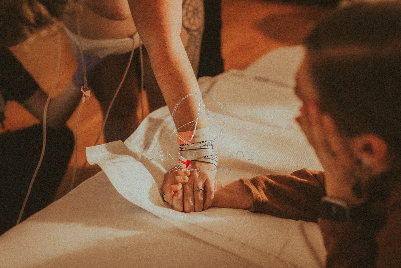 Details of expecting parents holding hands in the hospital bed