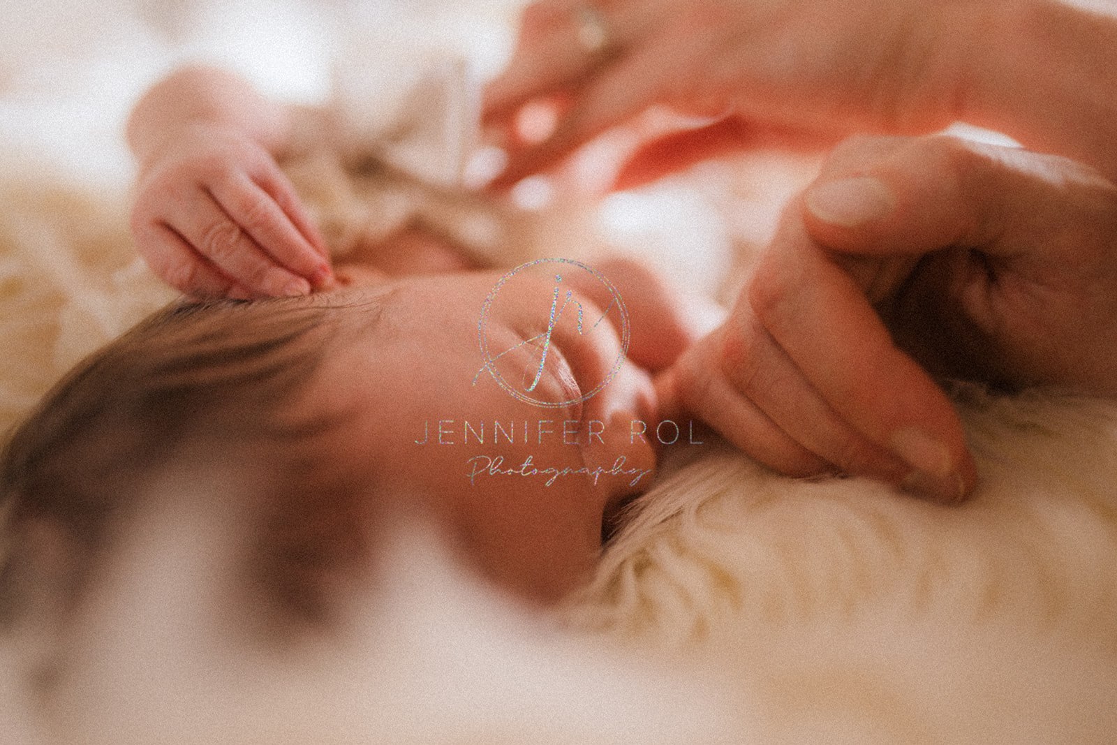 Details of a newborn baby sucking mom's pinky while laying on a fur blanket