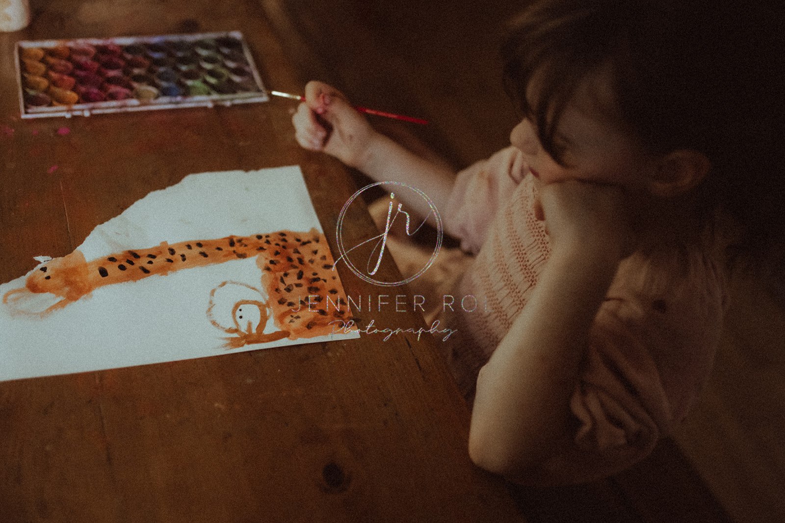 A young girl paints a giraffe with watercolor at a wooden table after visiting a Toy Store in Missoula