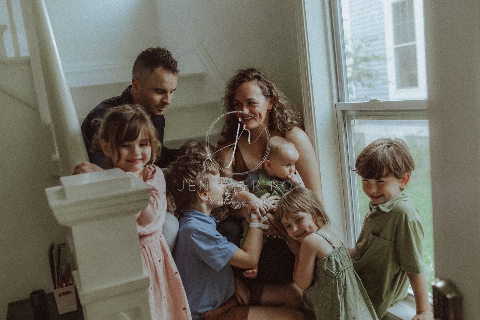 Happy mom and dad sit on the stairs with their 6 toddlers all playing and giggling around them after visiting trampoline park in Missoula