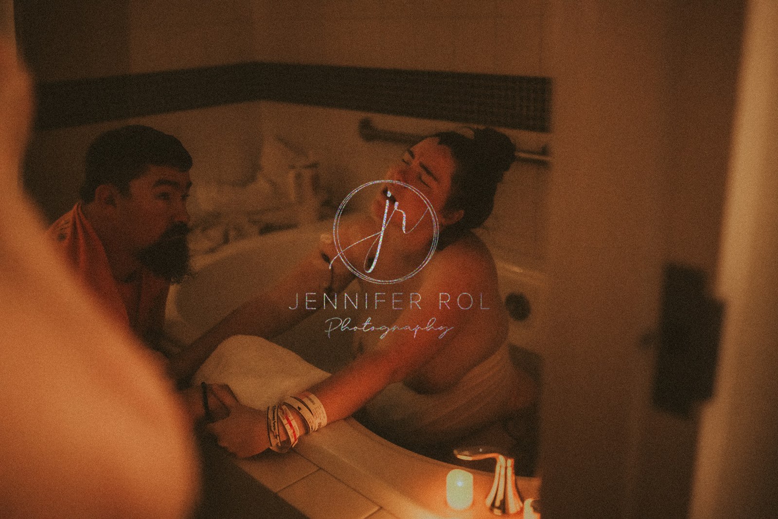 A mom in labor in a tub with dad holding hands being watched by Feral Mother Doula