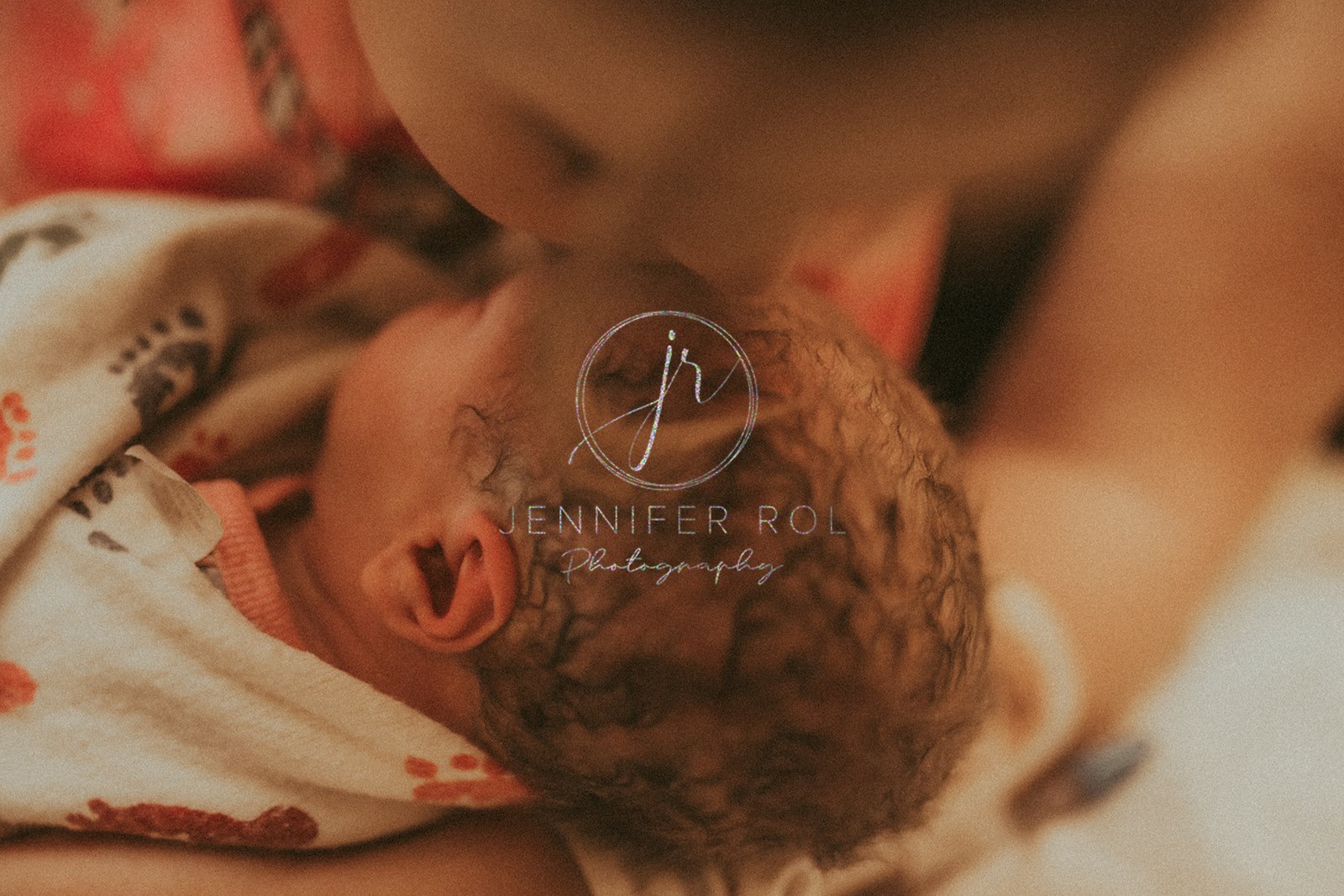 A mom kisses newborn's head in footprint swaddle after using Heart Strong Midwifery