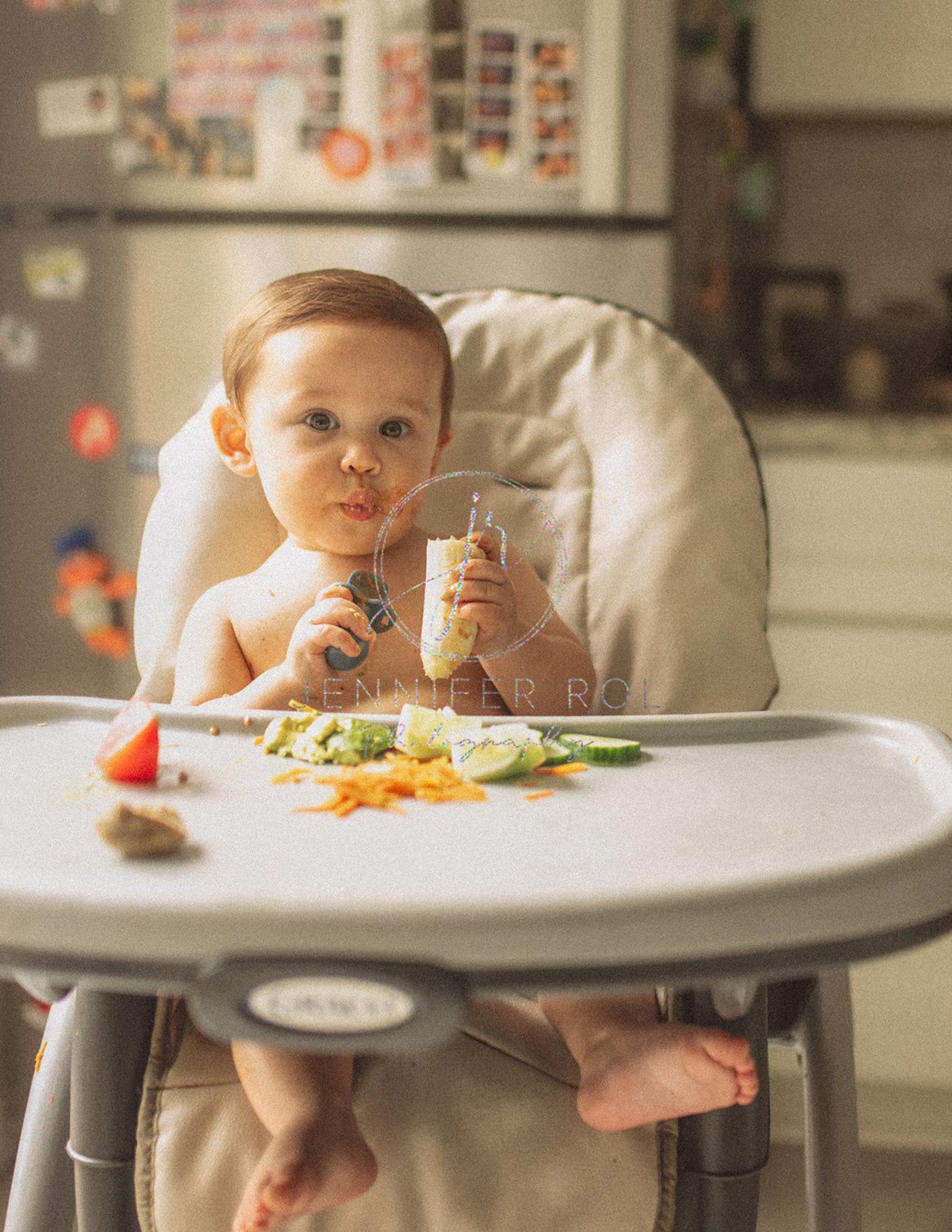 A happy baby eats a banana in a high chair in the kitchen after mom found baby furniture in Missoula, MT