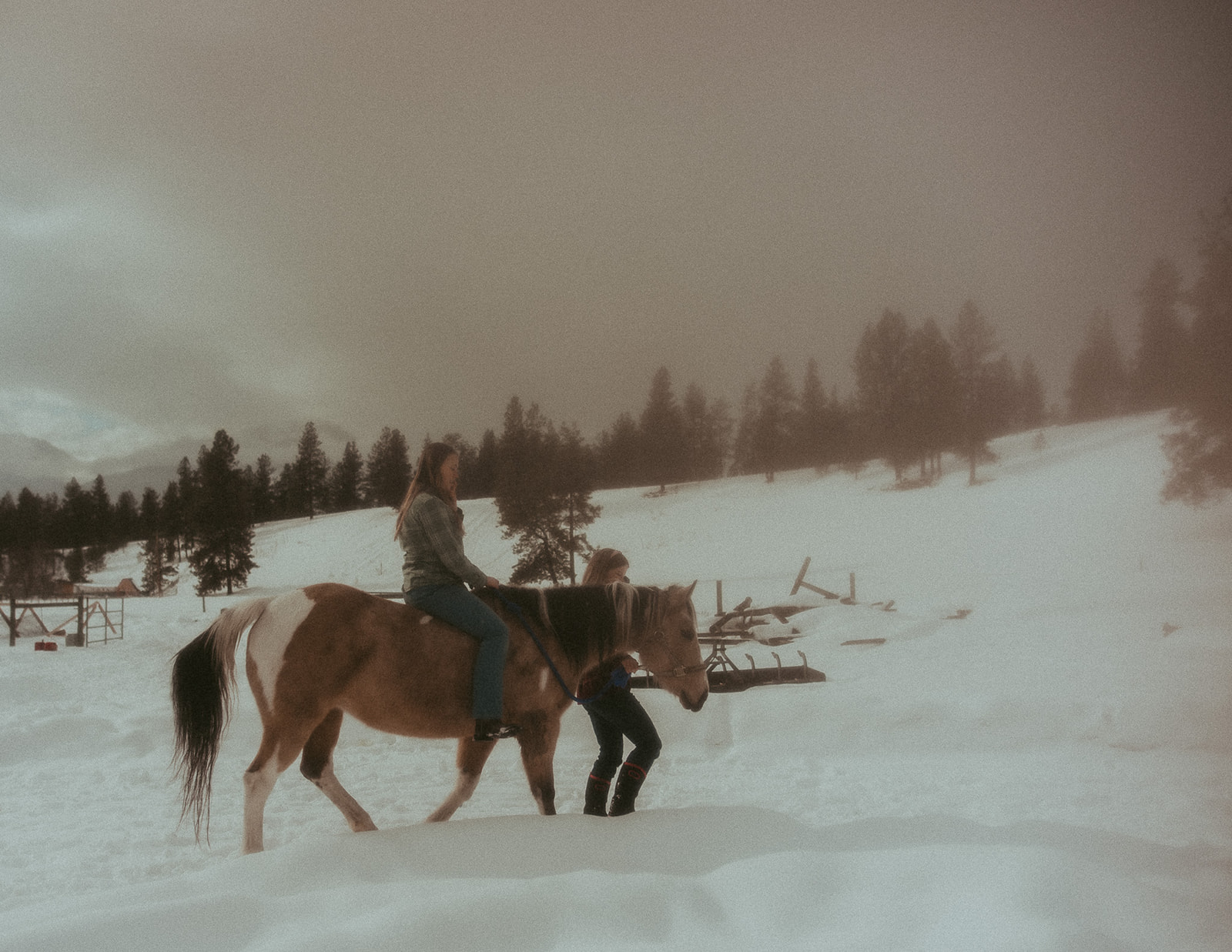 A woman rides a horse through the snow as her partner walks with them after visiting EmPower Place