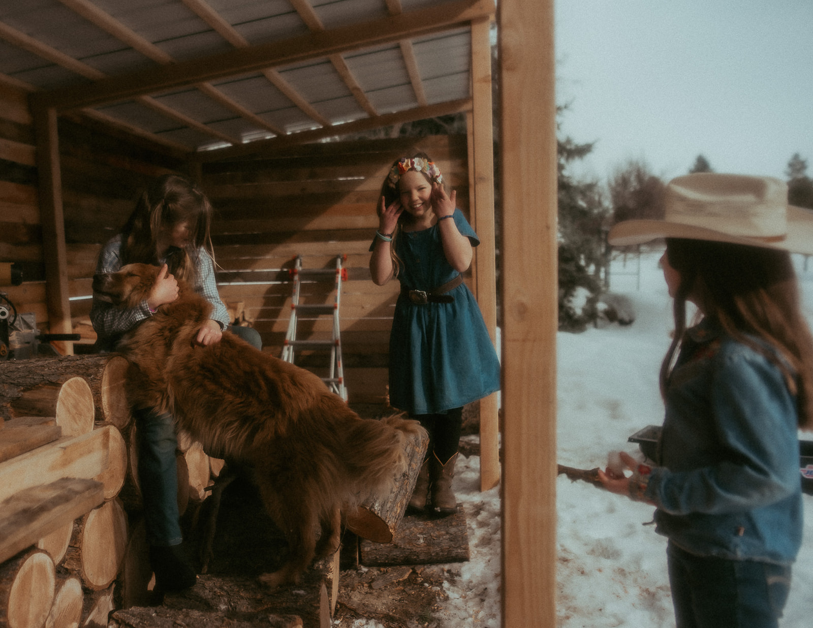 Three young girls play with a dog in a wood shed on a snowy day after visiting BASE Missoula