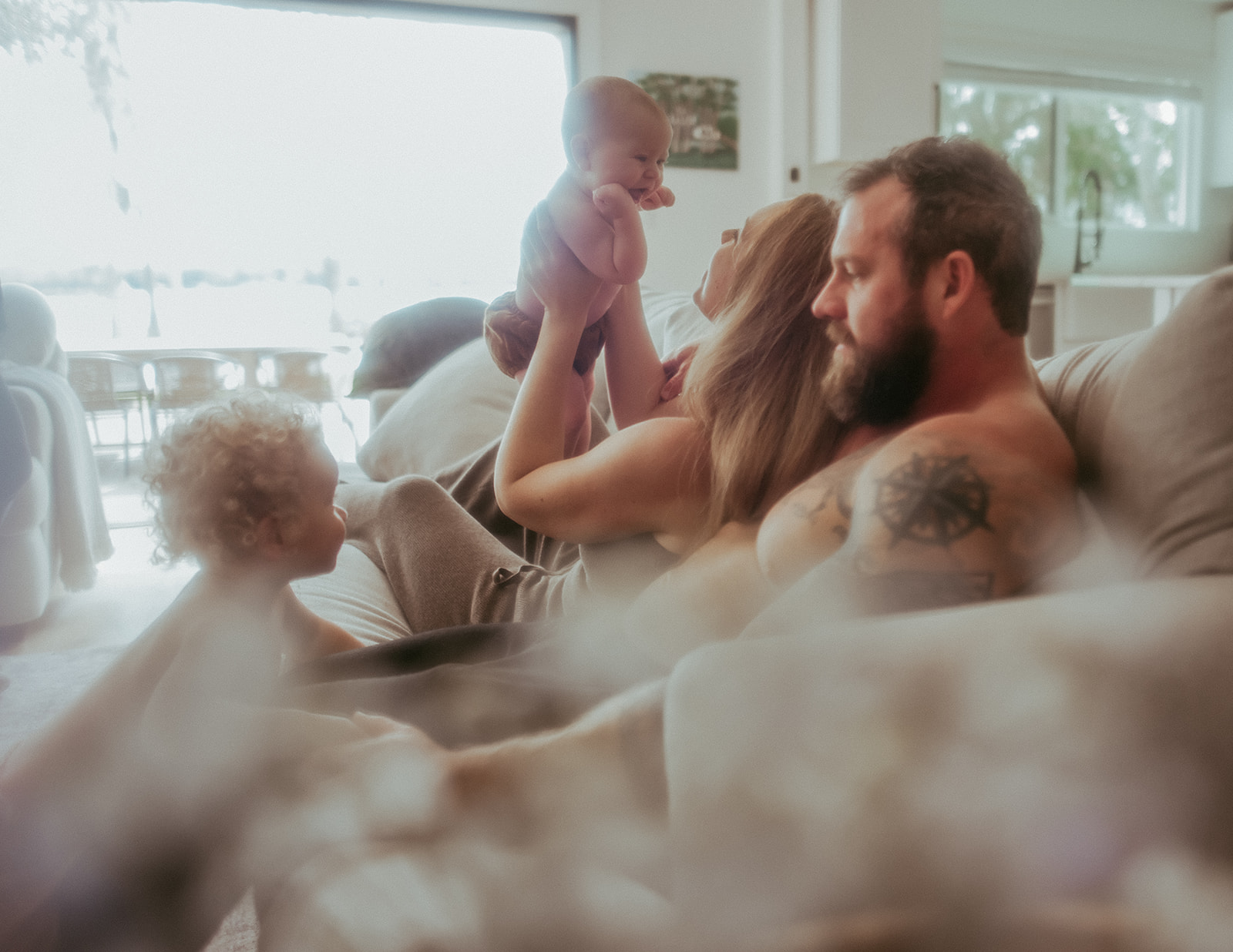 A mom and dad sit on a couch while playing with their two babies before attending Grow Music Missoula
