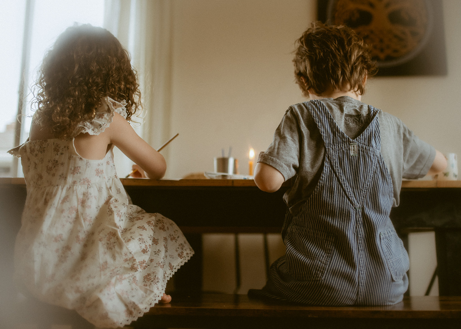 Toddler brother and sister paint together at the kitchen table