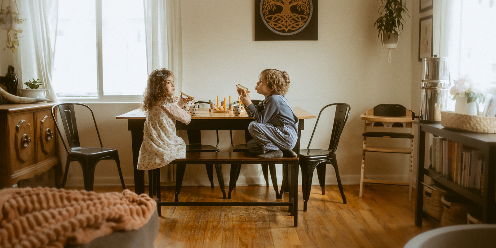Toddler brother and sister eat toast at the dining table together before visiting Spirit At Play Missoula