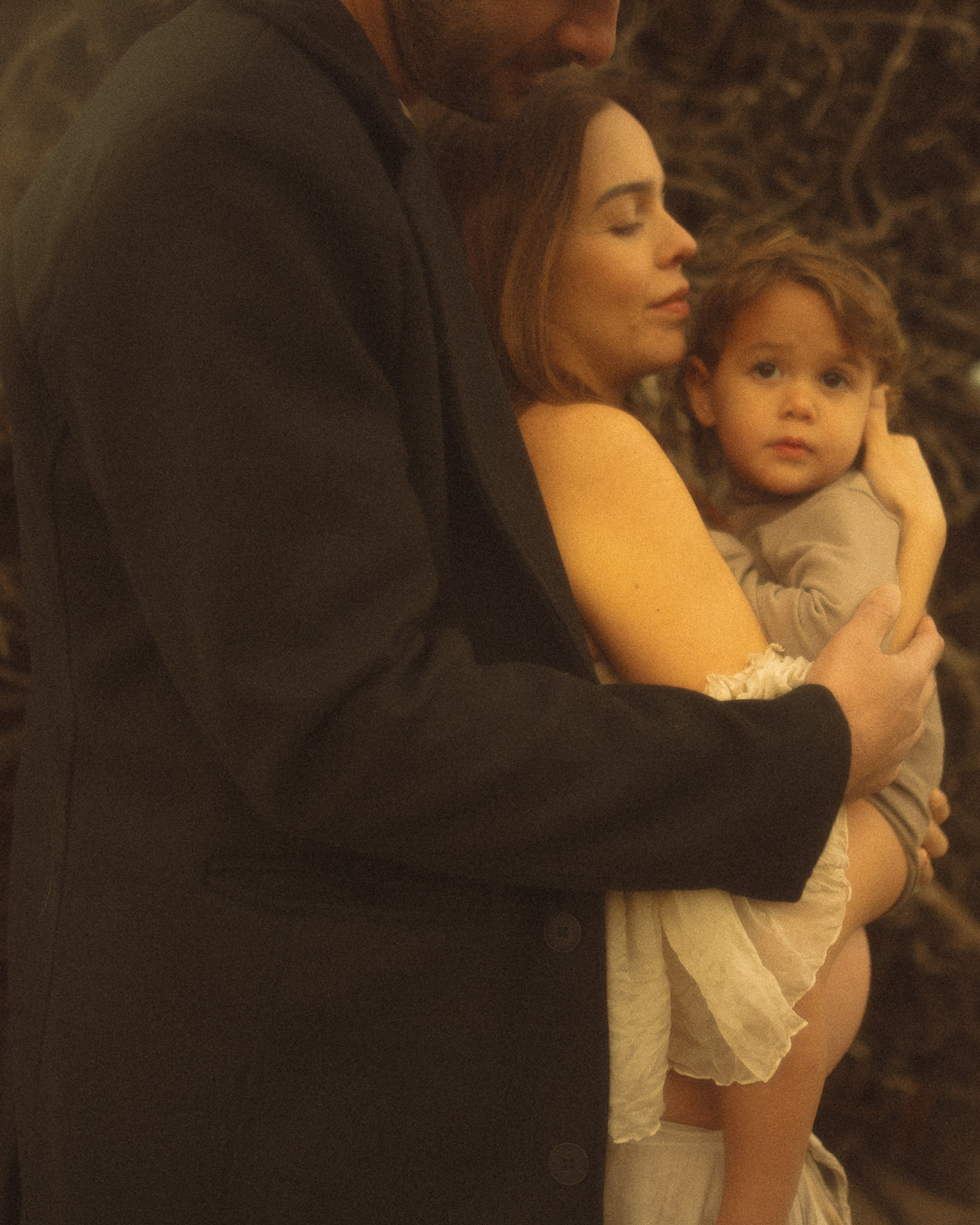 A happy couple snuggle with toddler on mom's pregnant bump