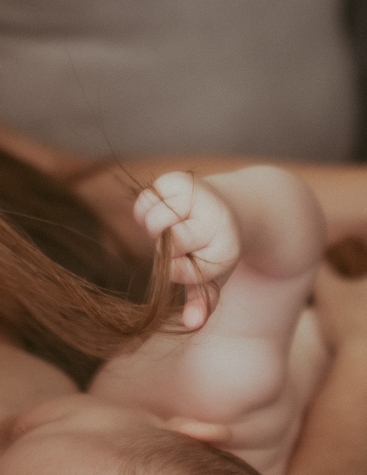 Details of a baby clutching mom's hair