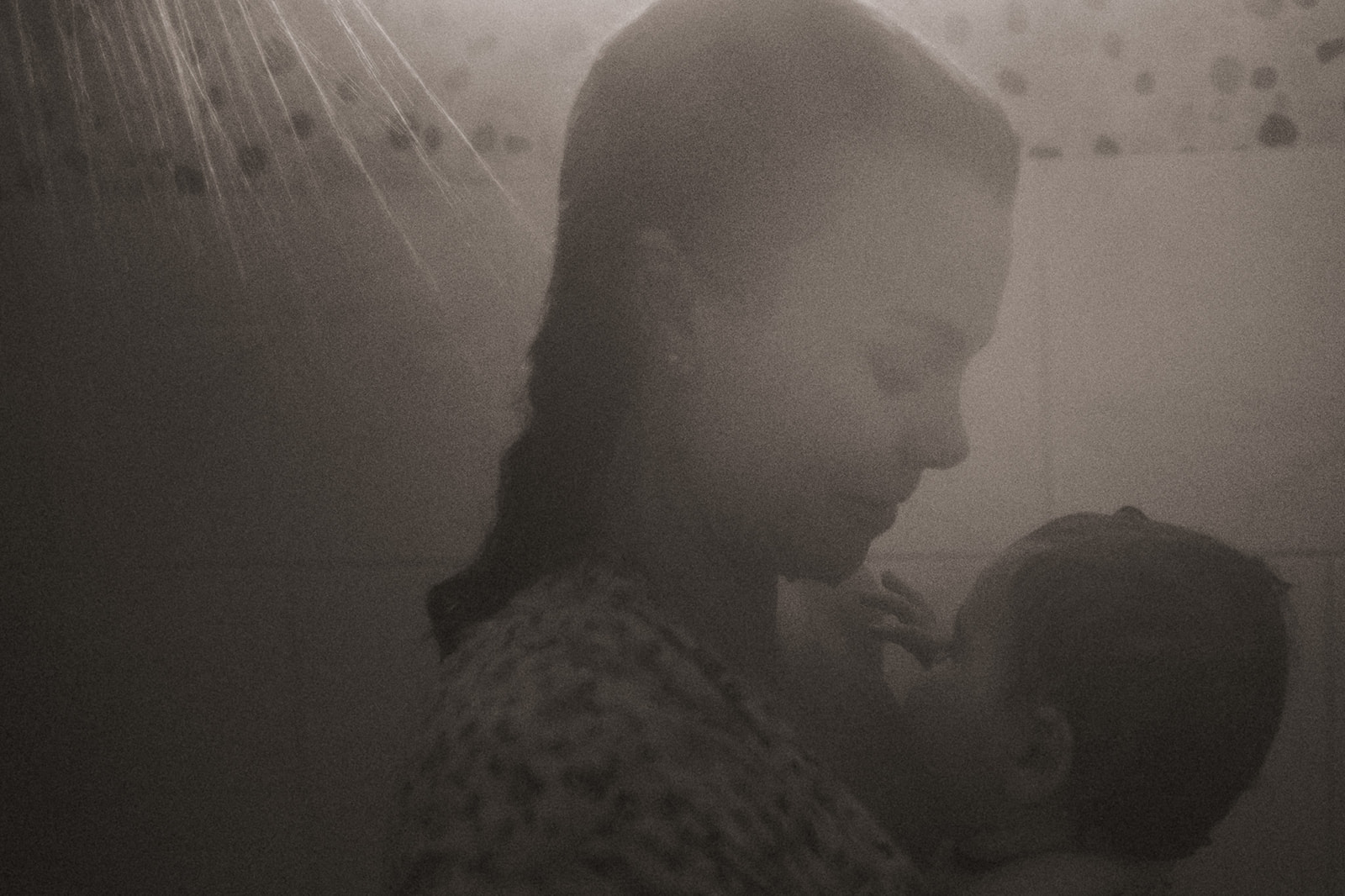 A smiling mother showers with her infant against her chest after using Nurse Family Partnership of Montana