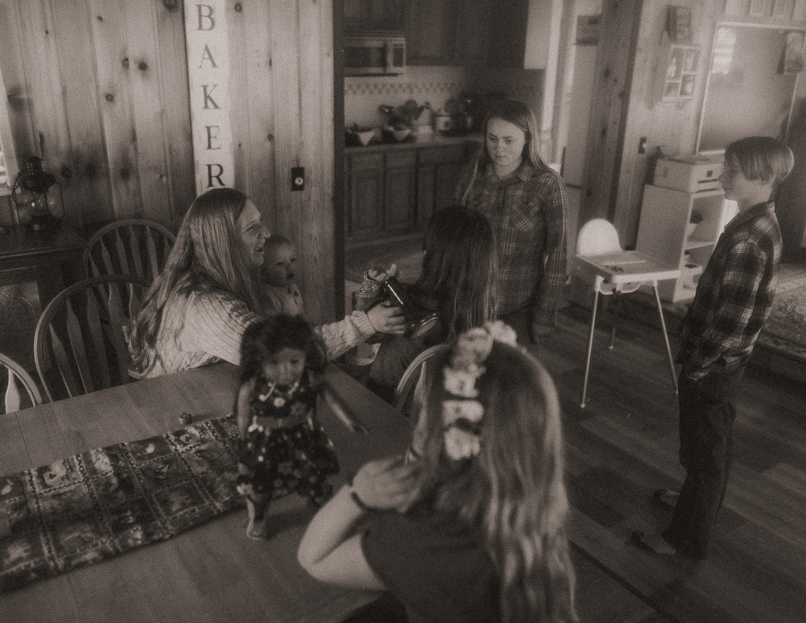 A mom plays with her four kids and baby in her lap in the dining room before visiting Farmers Markets in Missoula