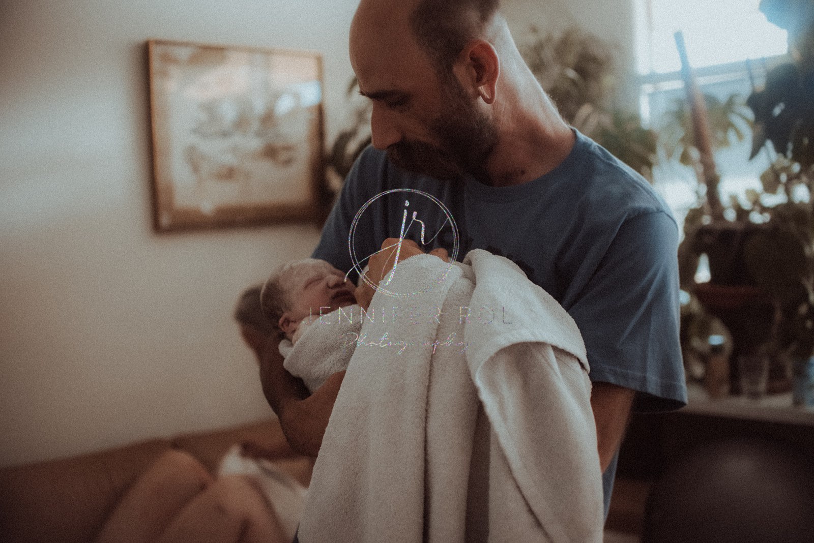 new dad looking at his newborn wrapped in a towel after birthing with a doula in hamilton mt