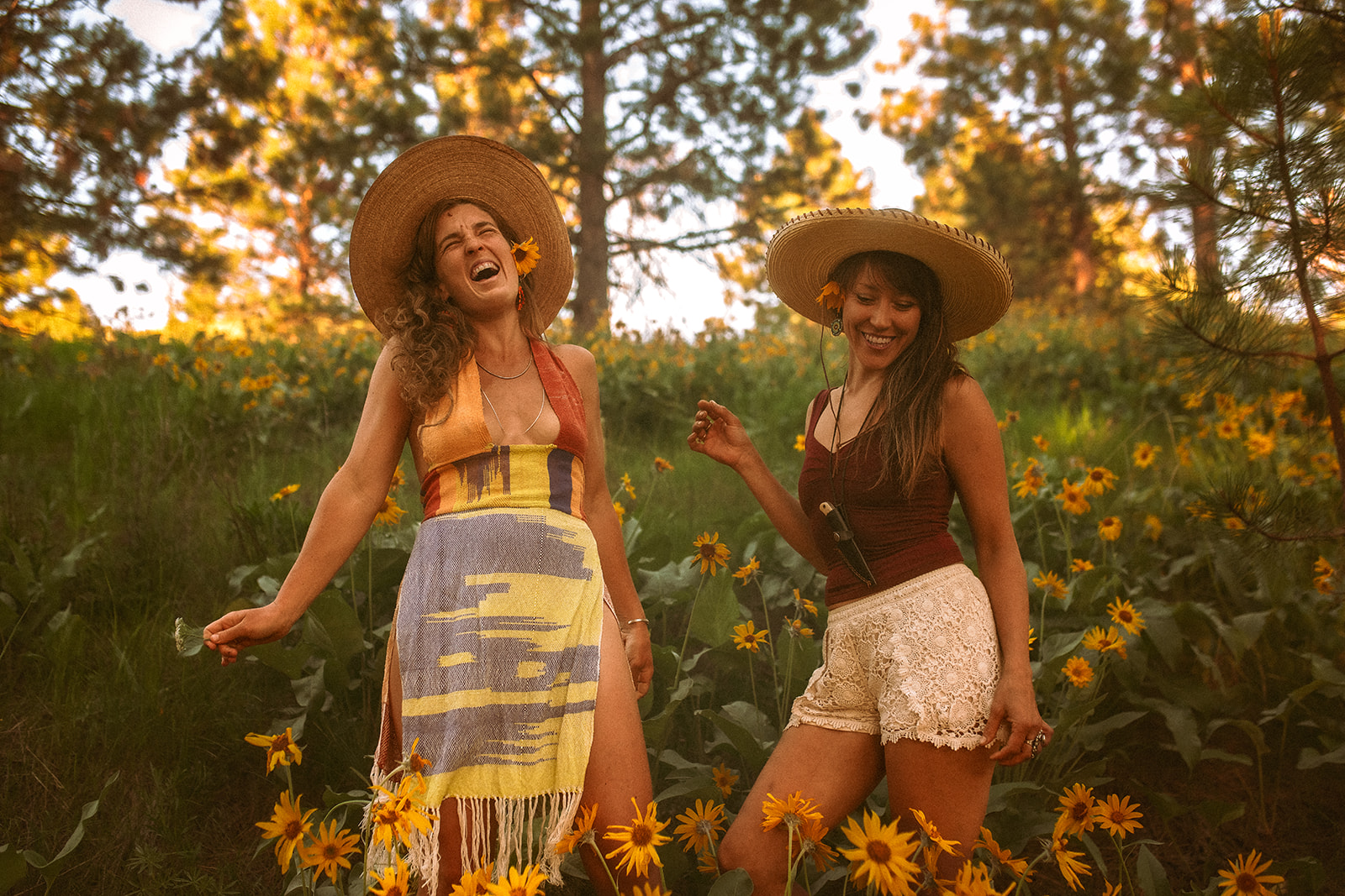 Two women laugh while exploring yellow wildflowers in a forest after finding an OBGYN in Hamilton, MT