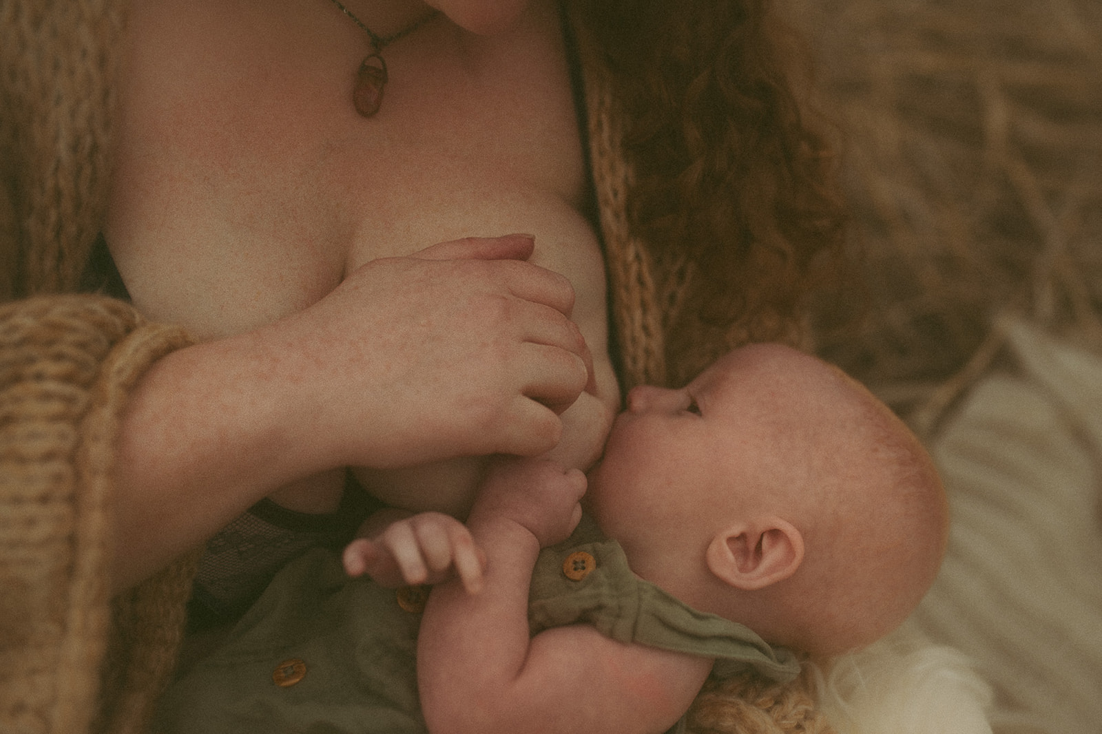 Details of an infant in a green onesie breastfeeding in a field on a picnic blanket after meeting pediatric dentists in Hamilton, MT