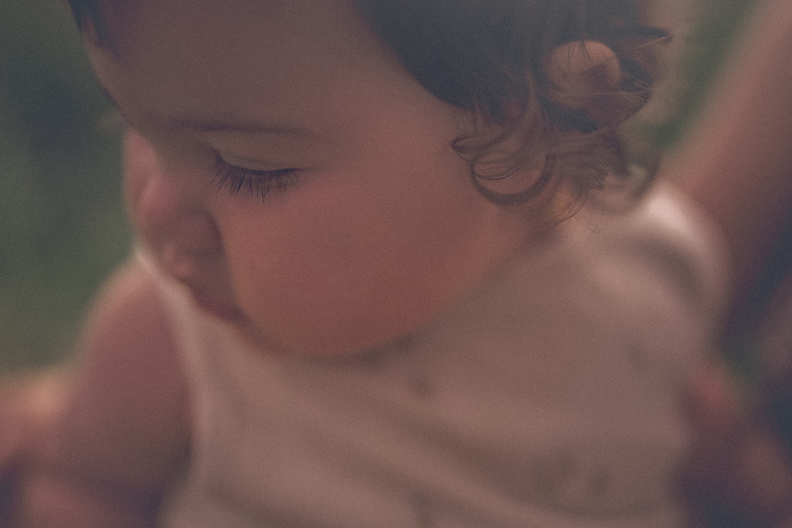 Details of an infant girl's cheek as she examines wildflwoers