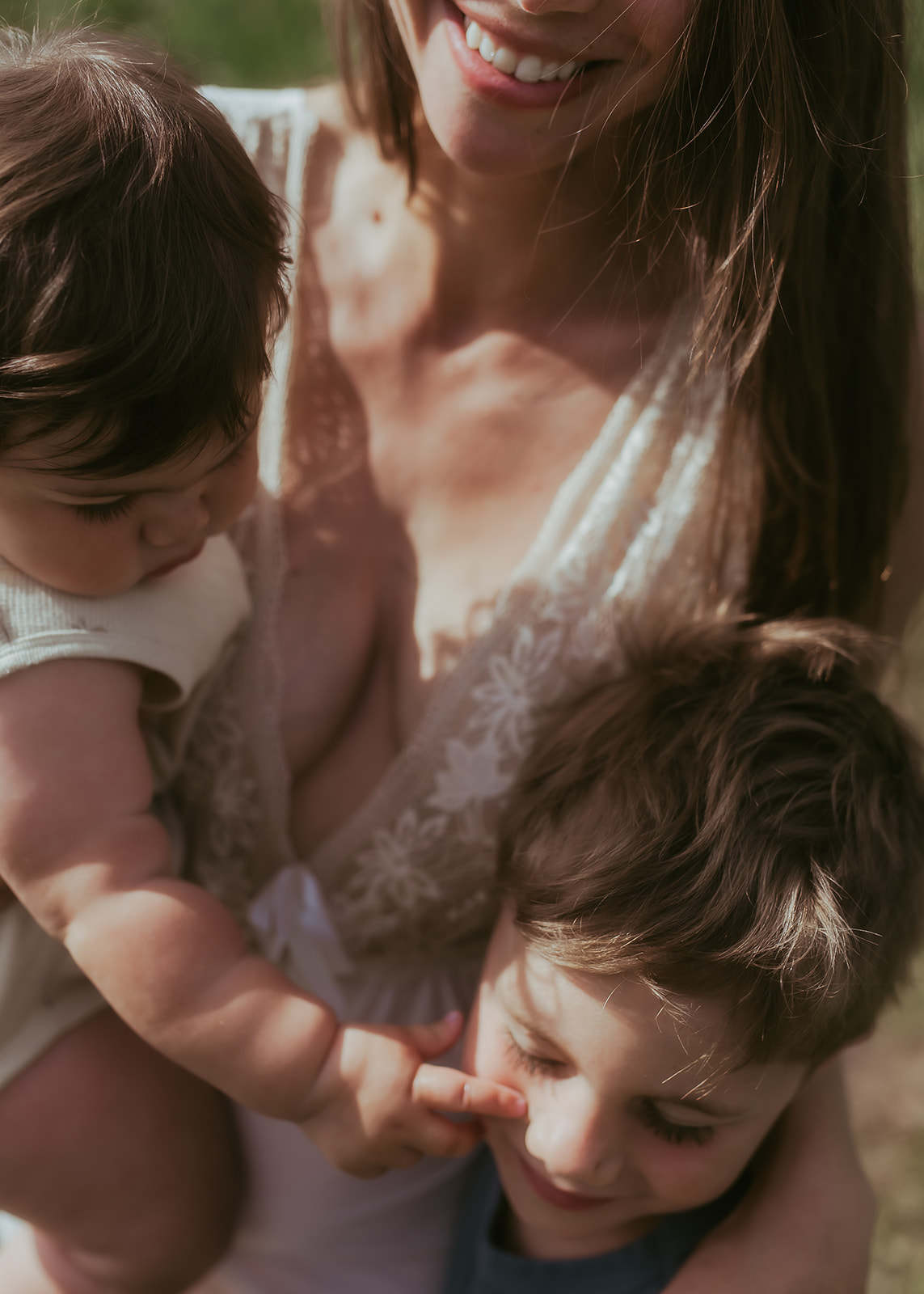 A moment with a mom baby and toddler laughing in a field after visiting birthday party places in Hamilton, MT