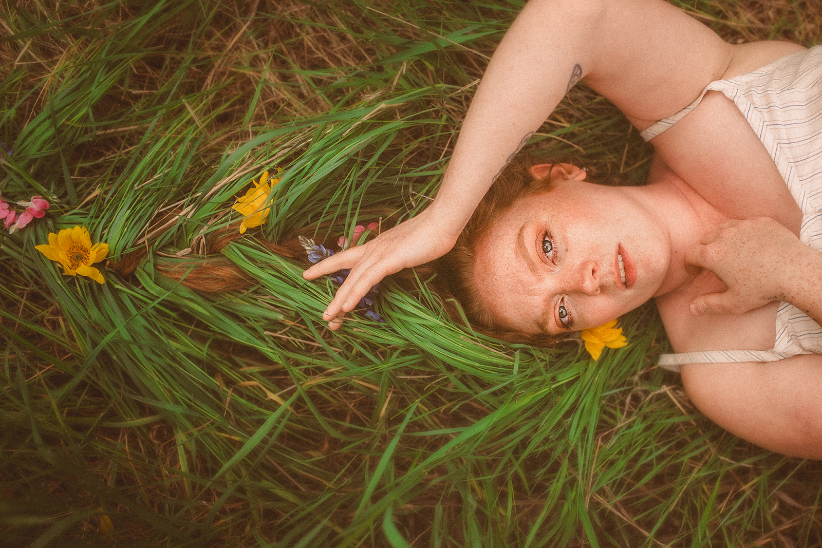 A pregnant woman lays in a bed of grass with a hand over her head after finding placenta encapsulation in Hamilton, MT