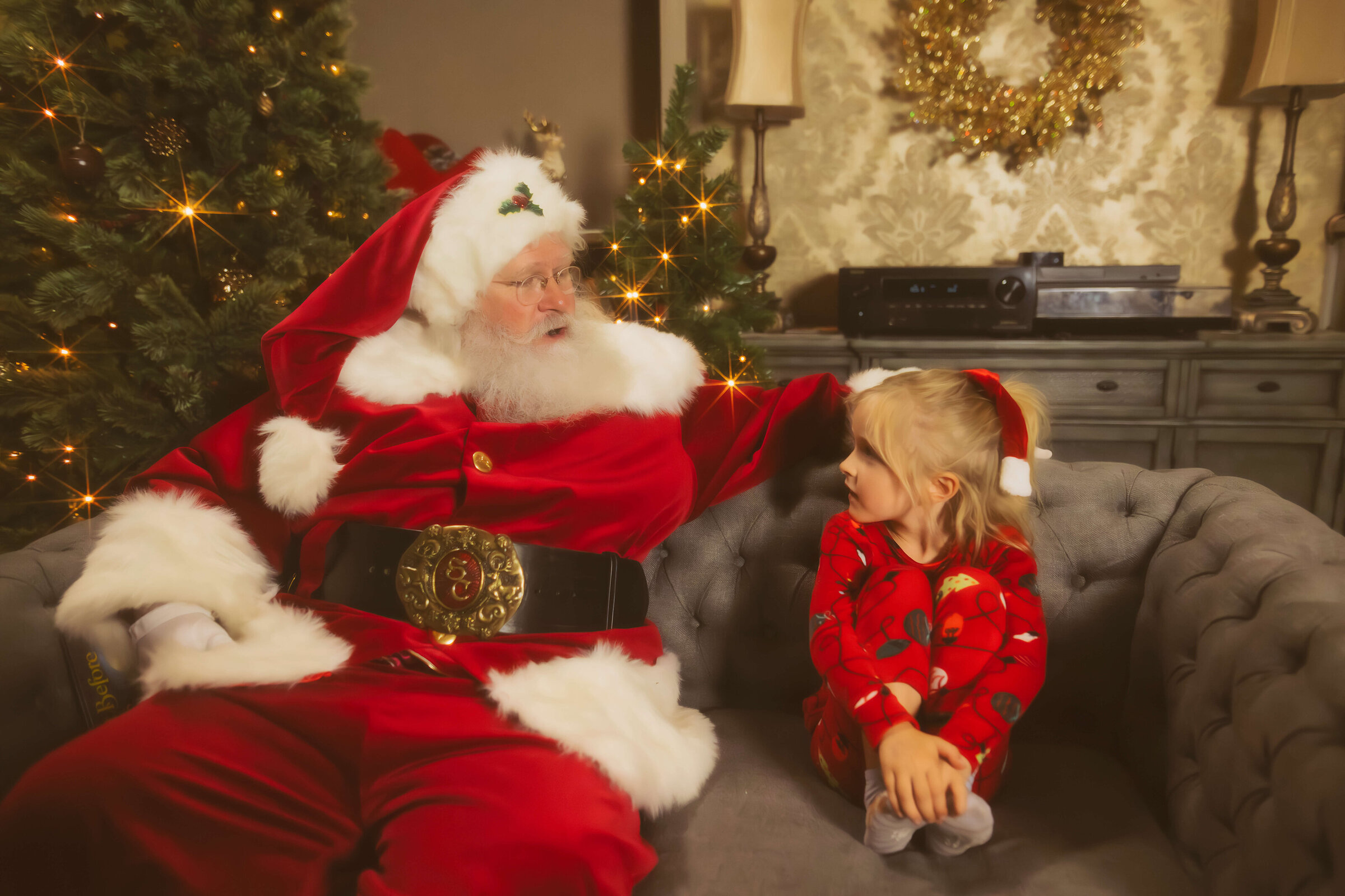 A young girl sits on a couch in red pajamas chatting with Santa before visiting missoula christmas markets
