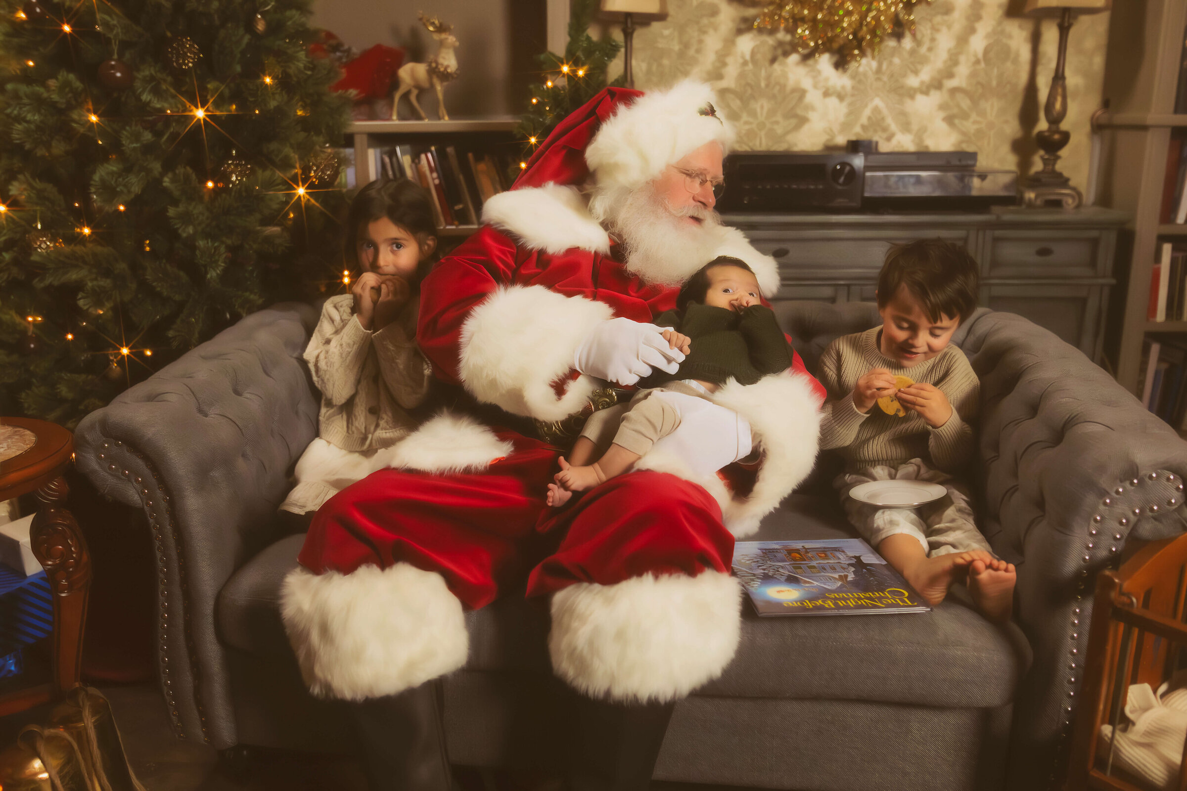 Santa sits on a couch with three young siblings eating cookies and laying in his lap before the missoula tree lighting