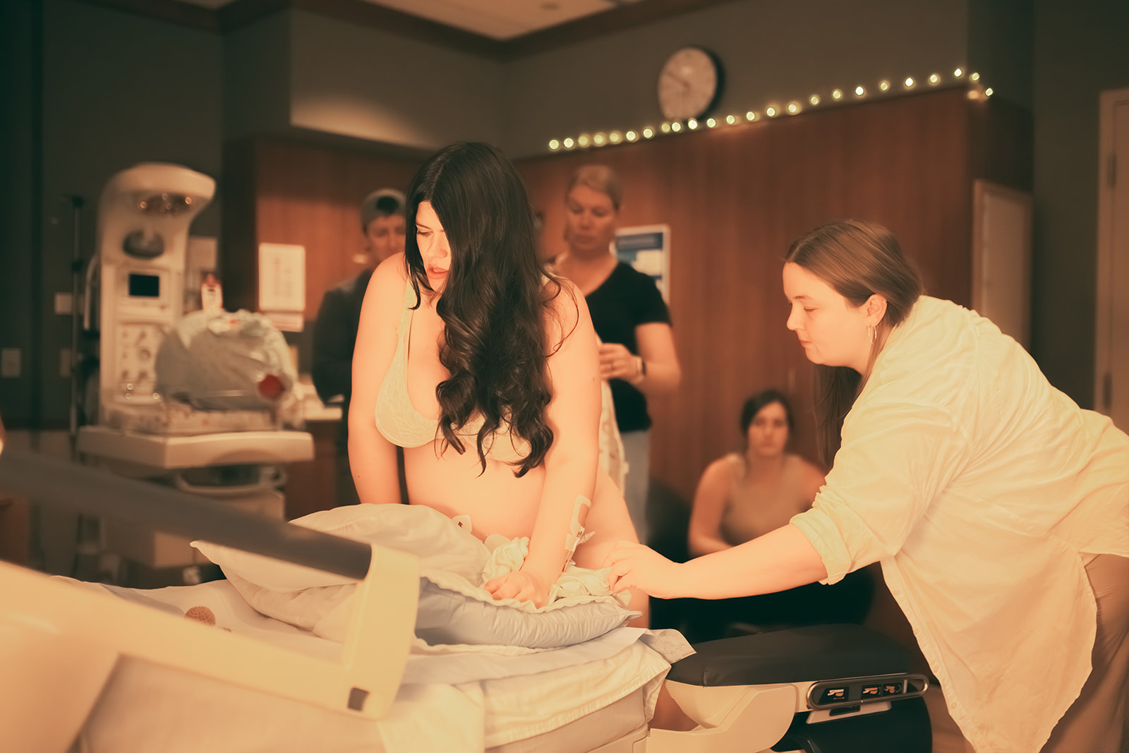 A mother to be in labor kneels on a bed as midwives guide her at one of the birth centers in Polson, MT