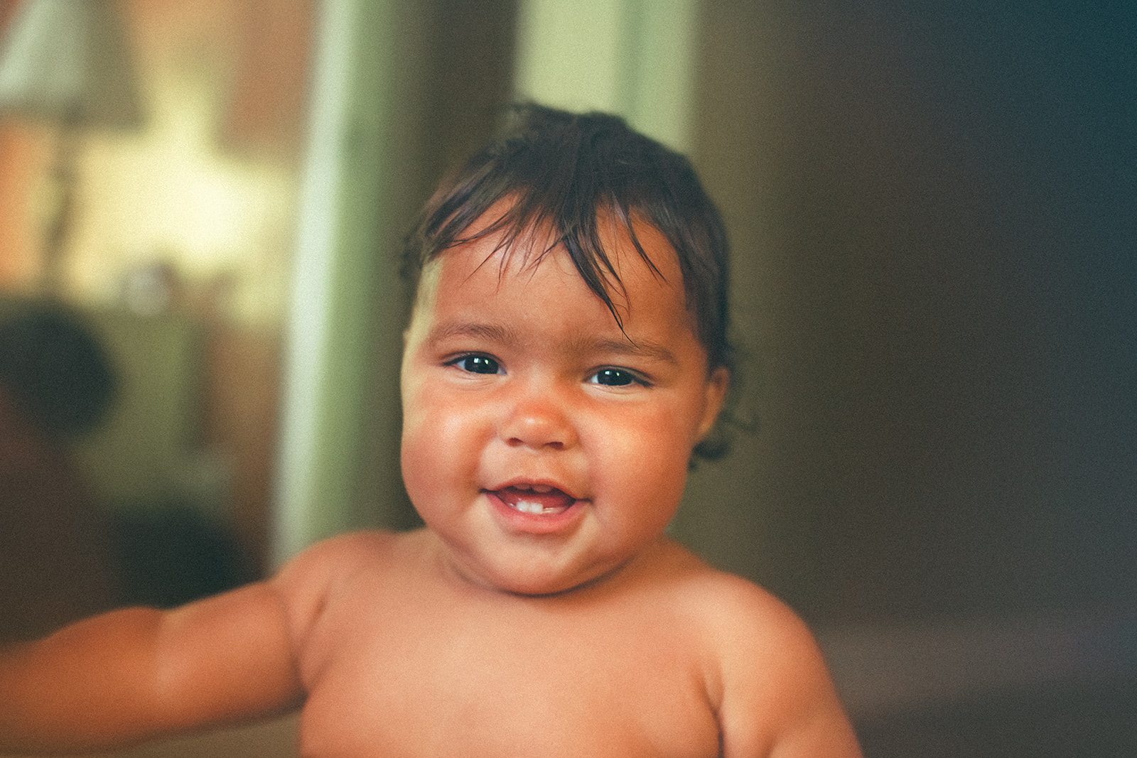 A happy baby smiles with a few teeth and no shirt
