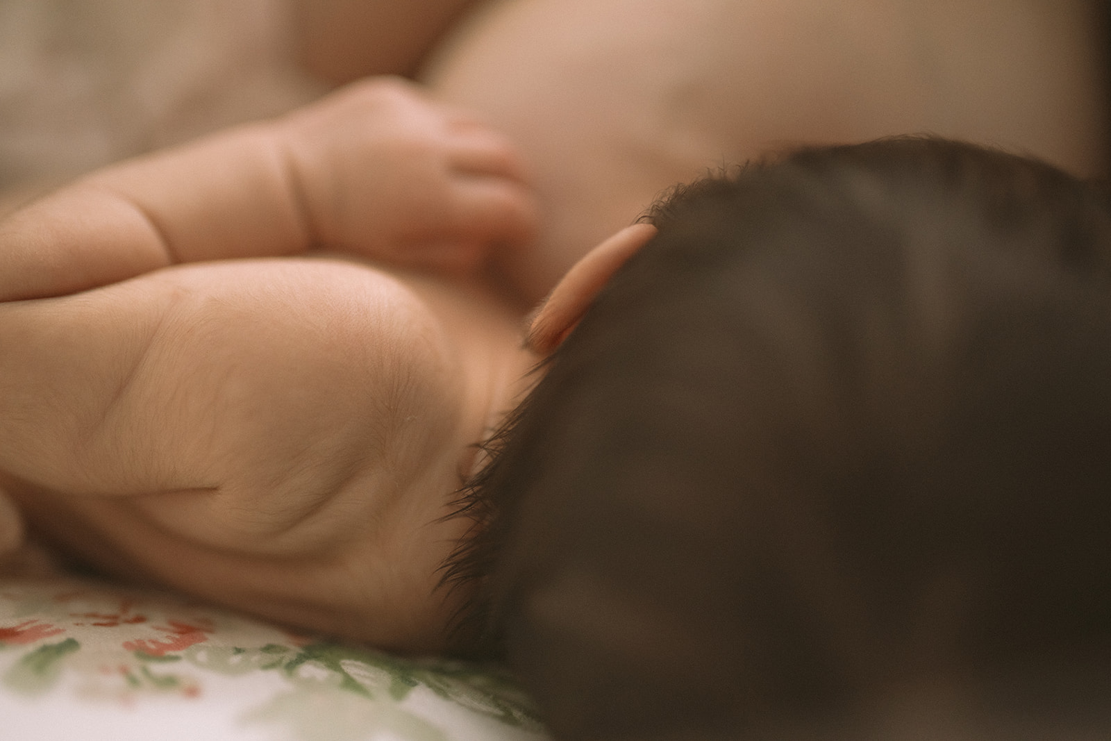 details of a newborn baby's shoulder as it lays in mom's arms against her chest