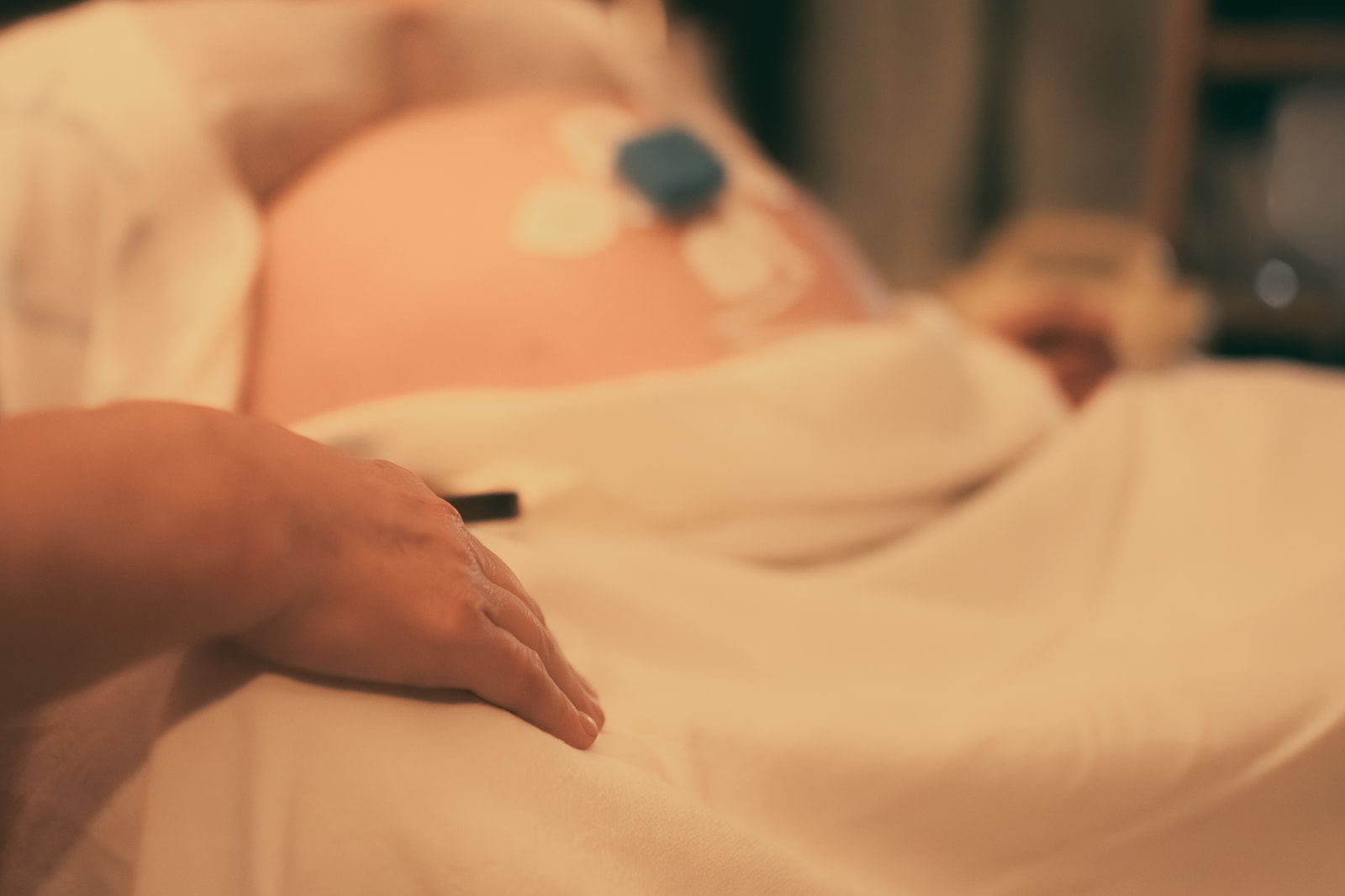 Details of a hand comforting a pregnant woman in labor