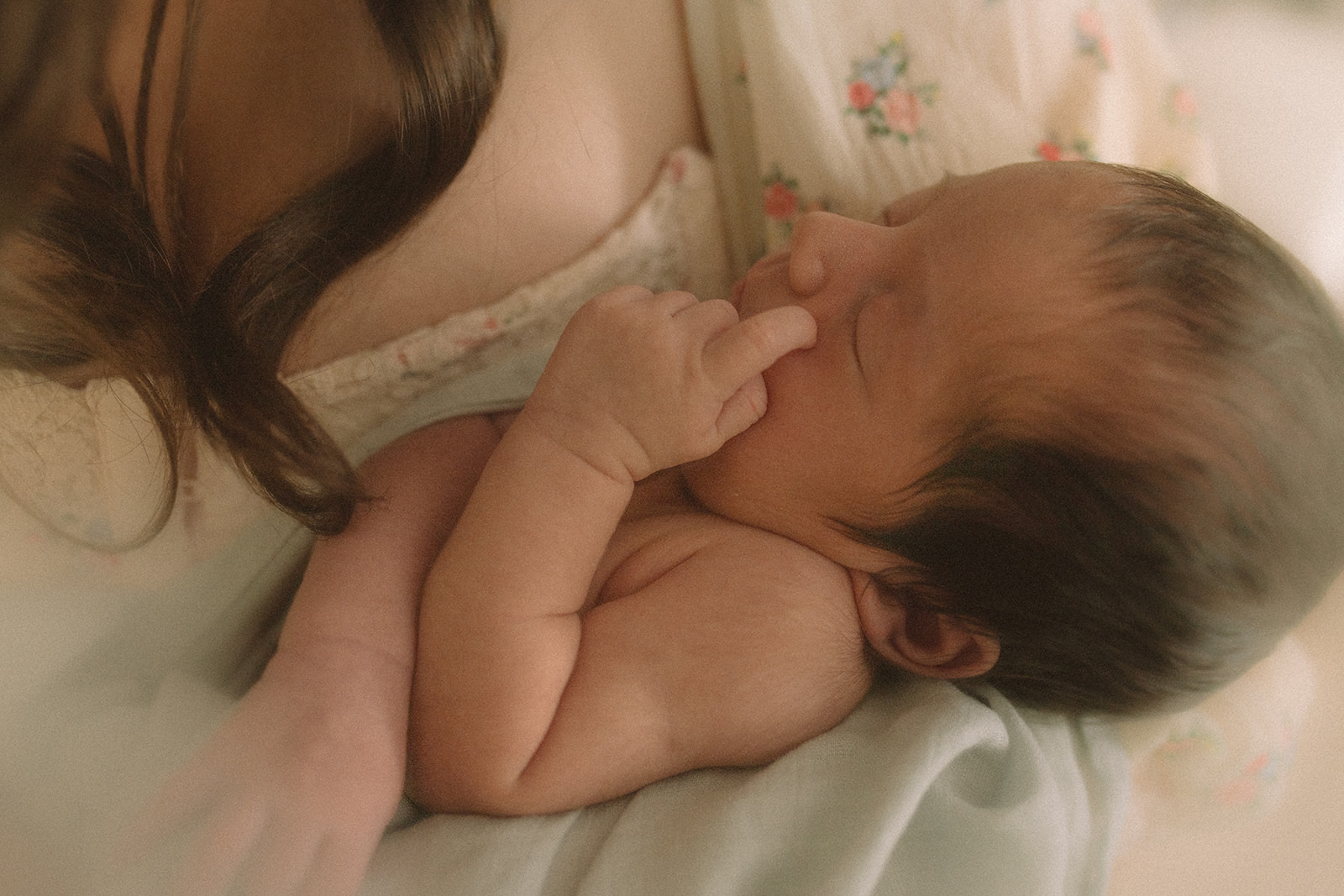 A newborn baby sleeps in mom's arms with a finger on its face before visiting pediatric dentists in Polson, MT