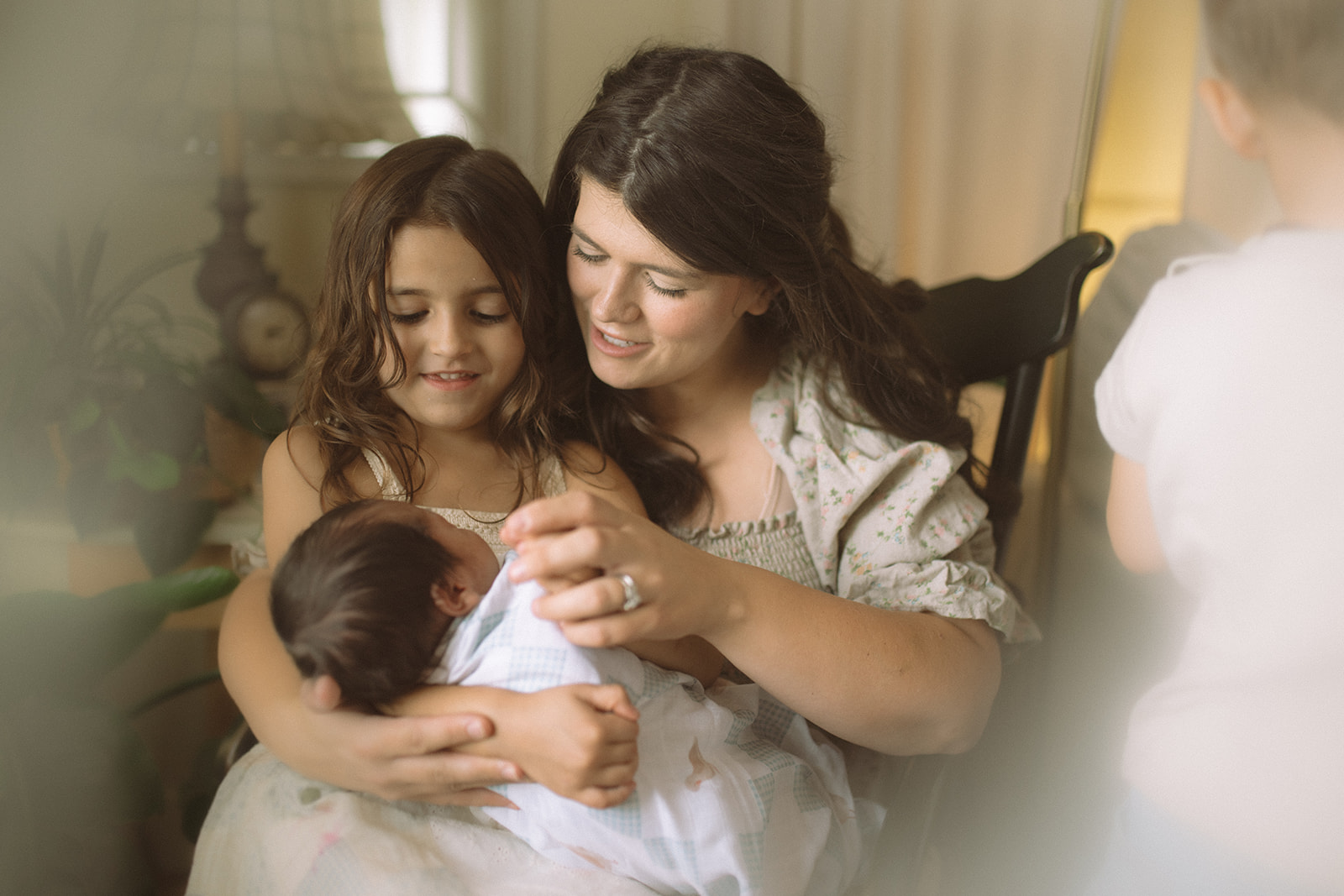 A mom sits in a rocking chair with her toddler and newborn in her lap after visiting pediatricians in Polson, MT