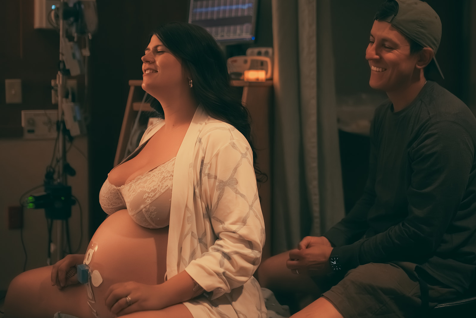 A pregnant couple in labor laugh while sitting in the delivery room thanks to midwives in Kalispell, MT