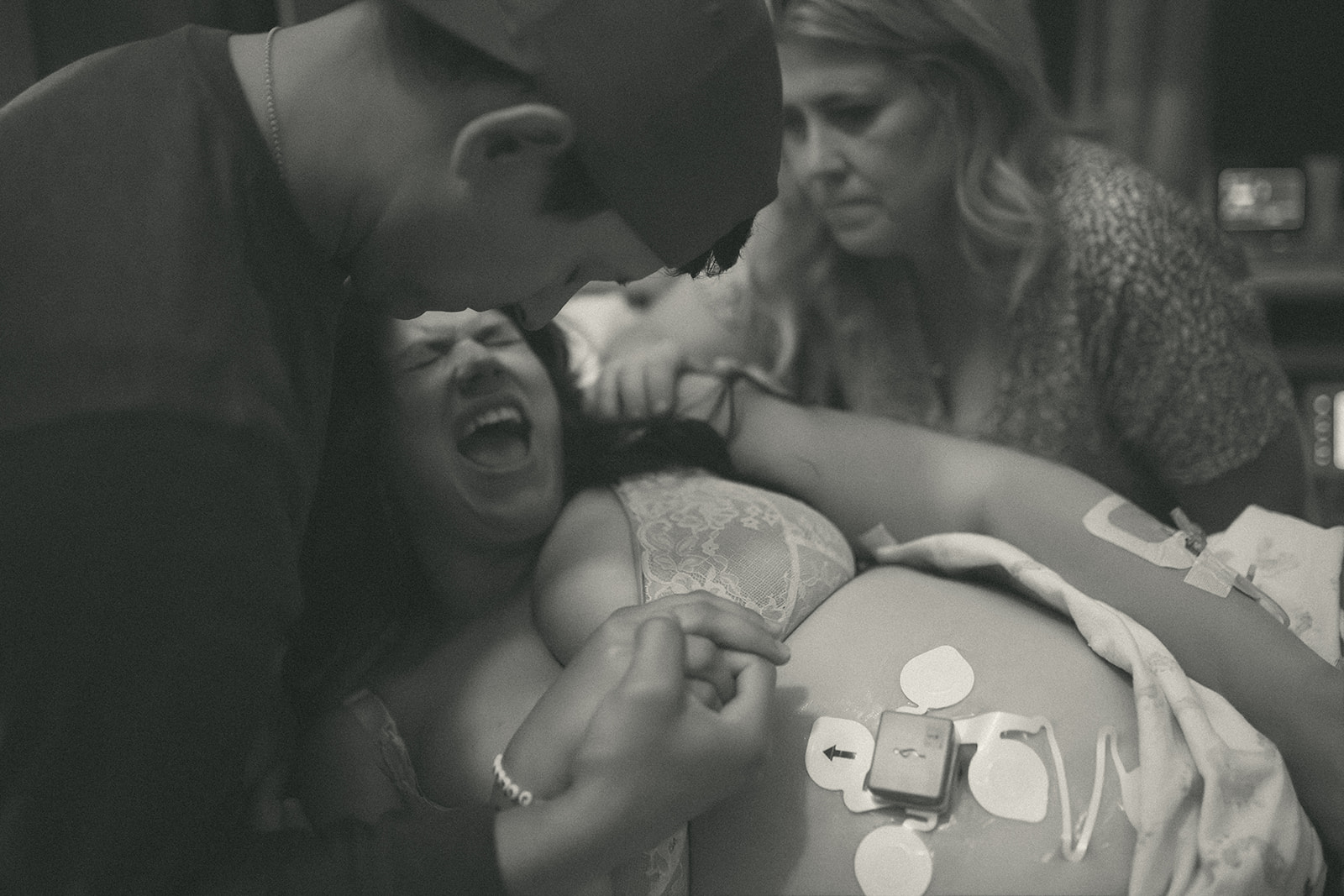 A mother to be screams while in labor covered in sensors and medical stickies